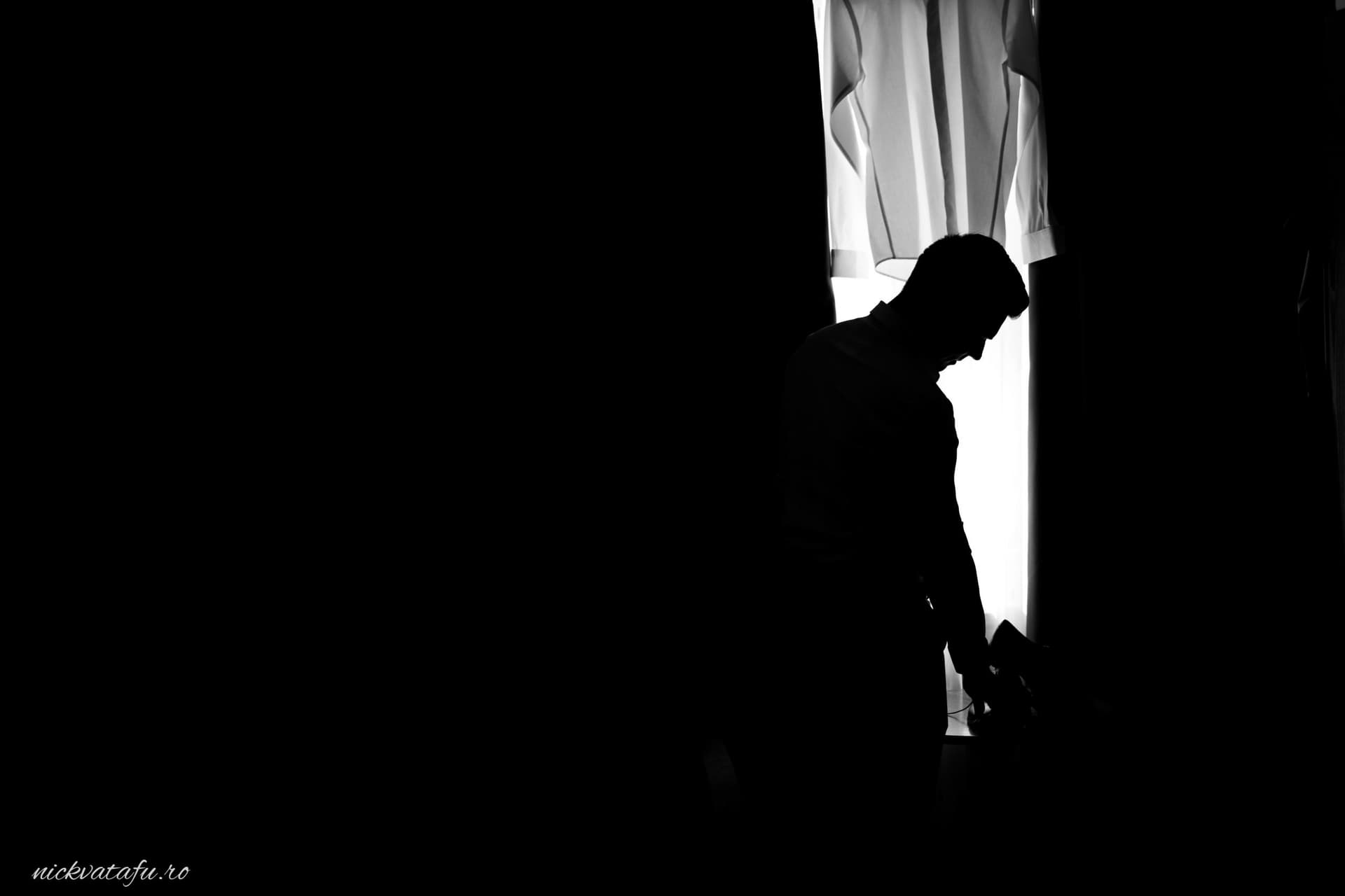 Silhouette a unui bărbat în fața unei feronerie, evocând emoții profunde înainte de ceremonie, fotografie nuntă.