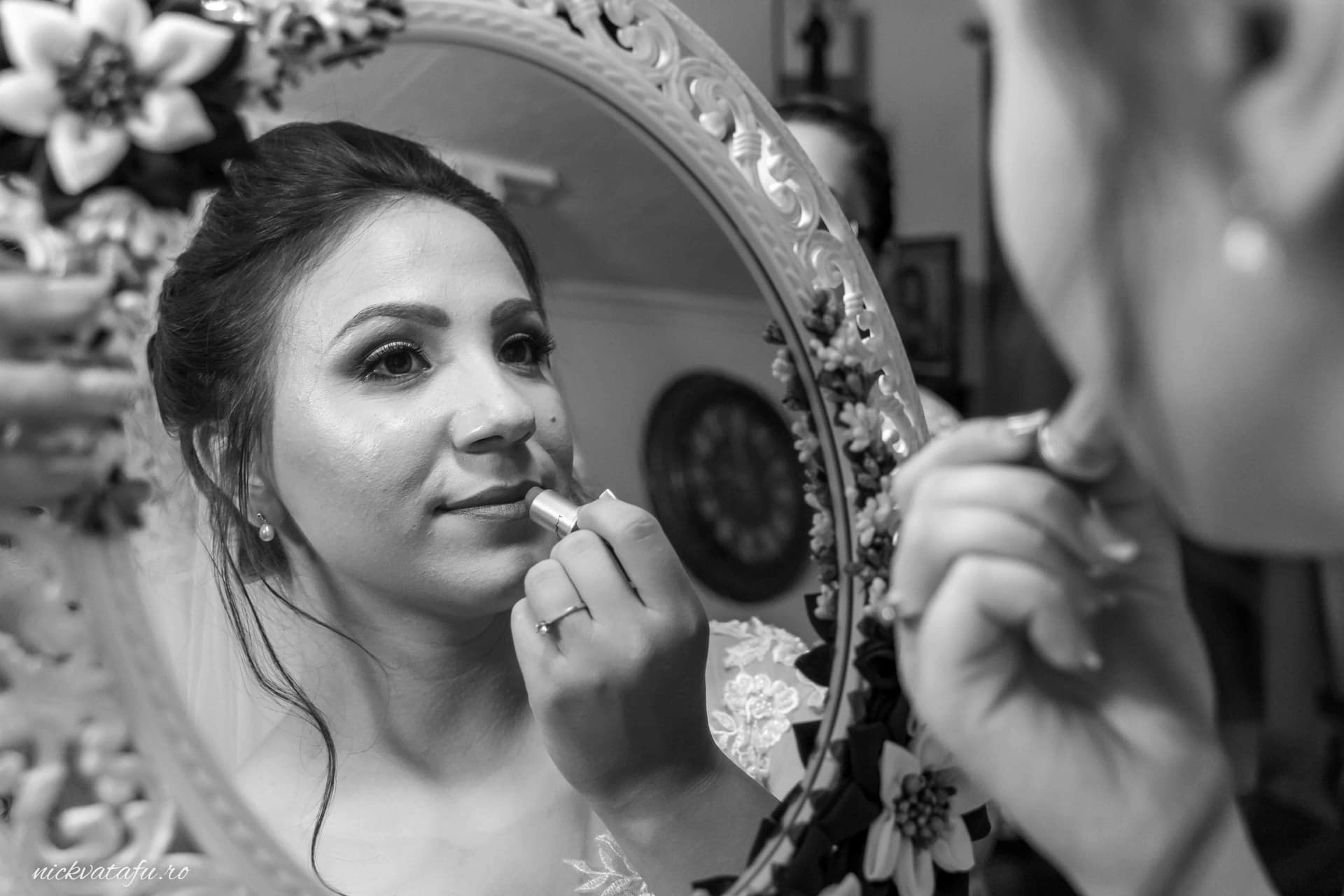 Mireasă aplicând ruj în fața oglinzii, emoție și pregătiri pentru o fotografie de nuntă elegantă.