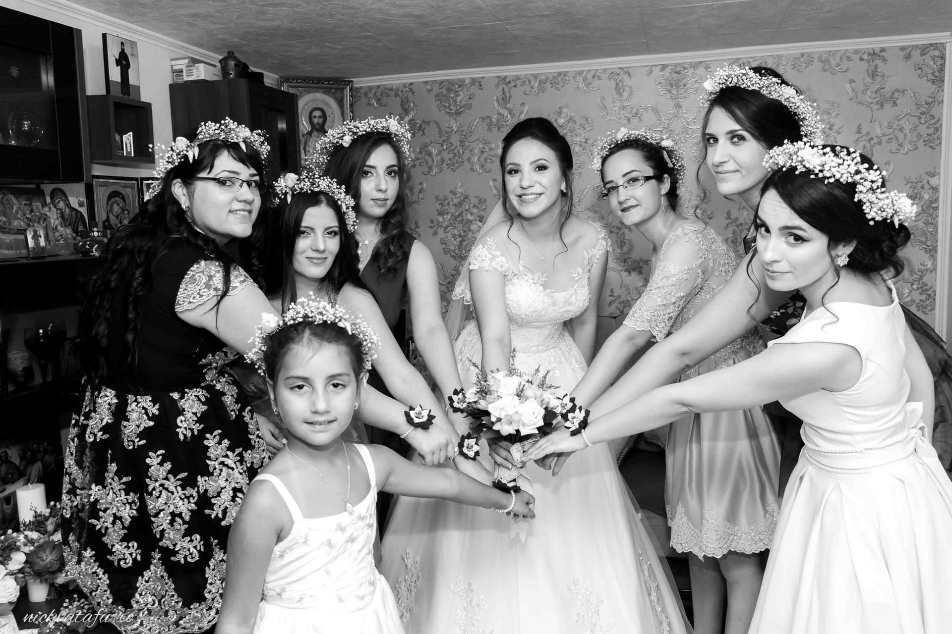 Mireasă înconjurată de domnișoare de onoare, zâmbete și emoție înainte de ceremonie, fotografie nuntă alb-negru.