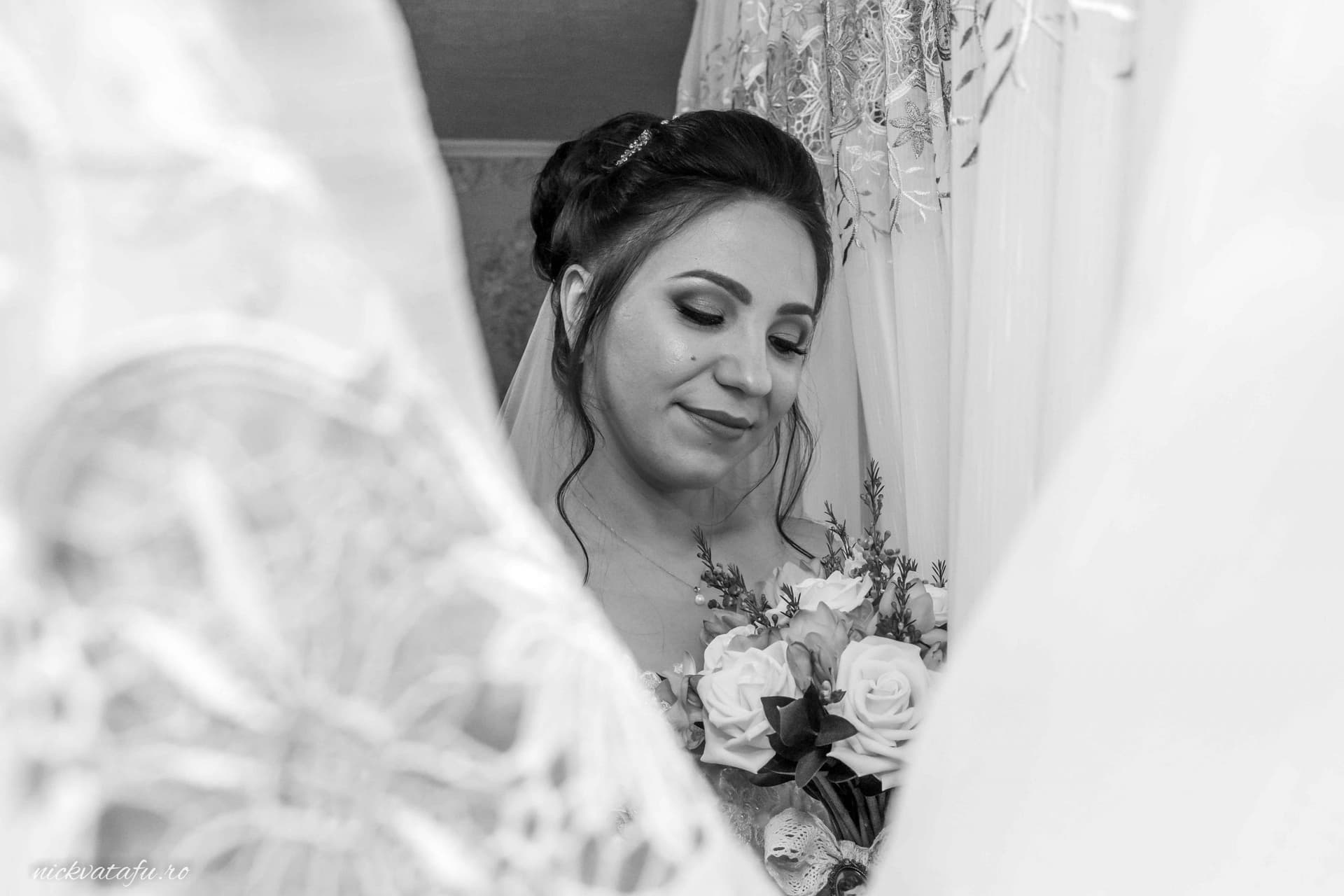 Mireasă emoționată, ținând buchetul de flori, surprinsă în detalii delicate înainte de ceremonie.