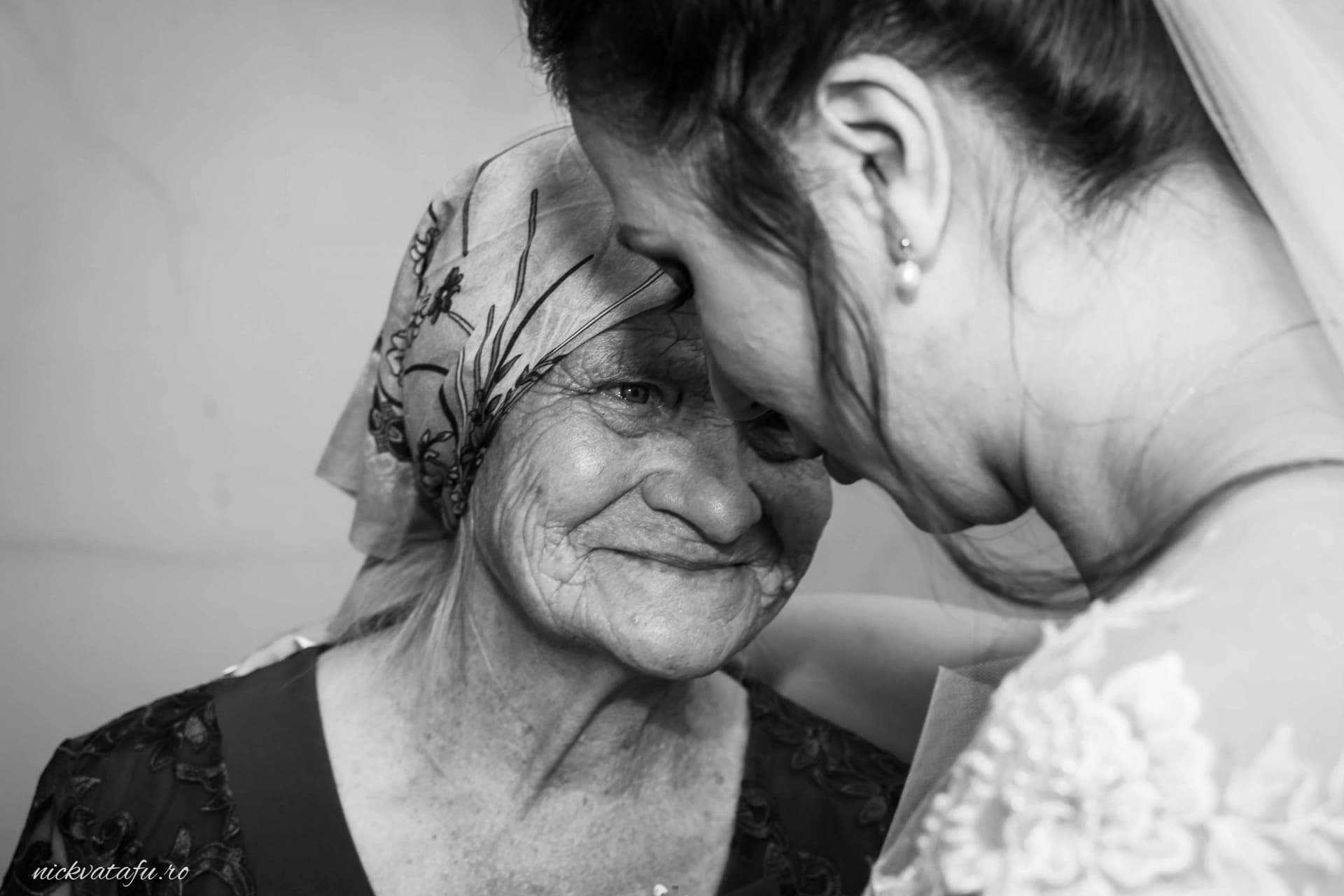 Îmbrățișare plină de emoție între mireasă și bunica ei, fotografie nuntă alb-negru, capturând dragostea și tradiția.