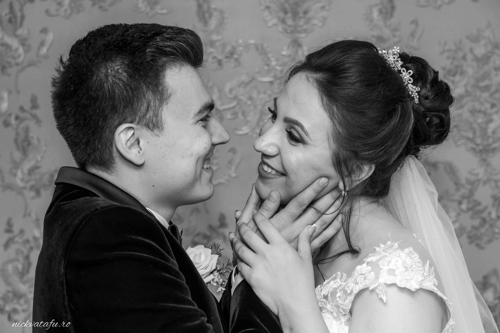 Mire și mireasă zâmbind unul altuia, plini de emoție, într-o fotografie de nuntă elegantă.