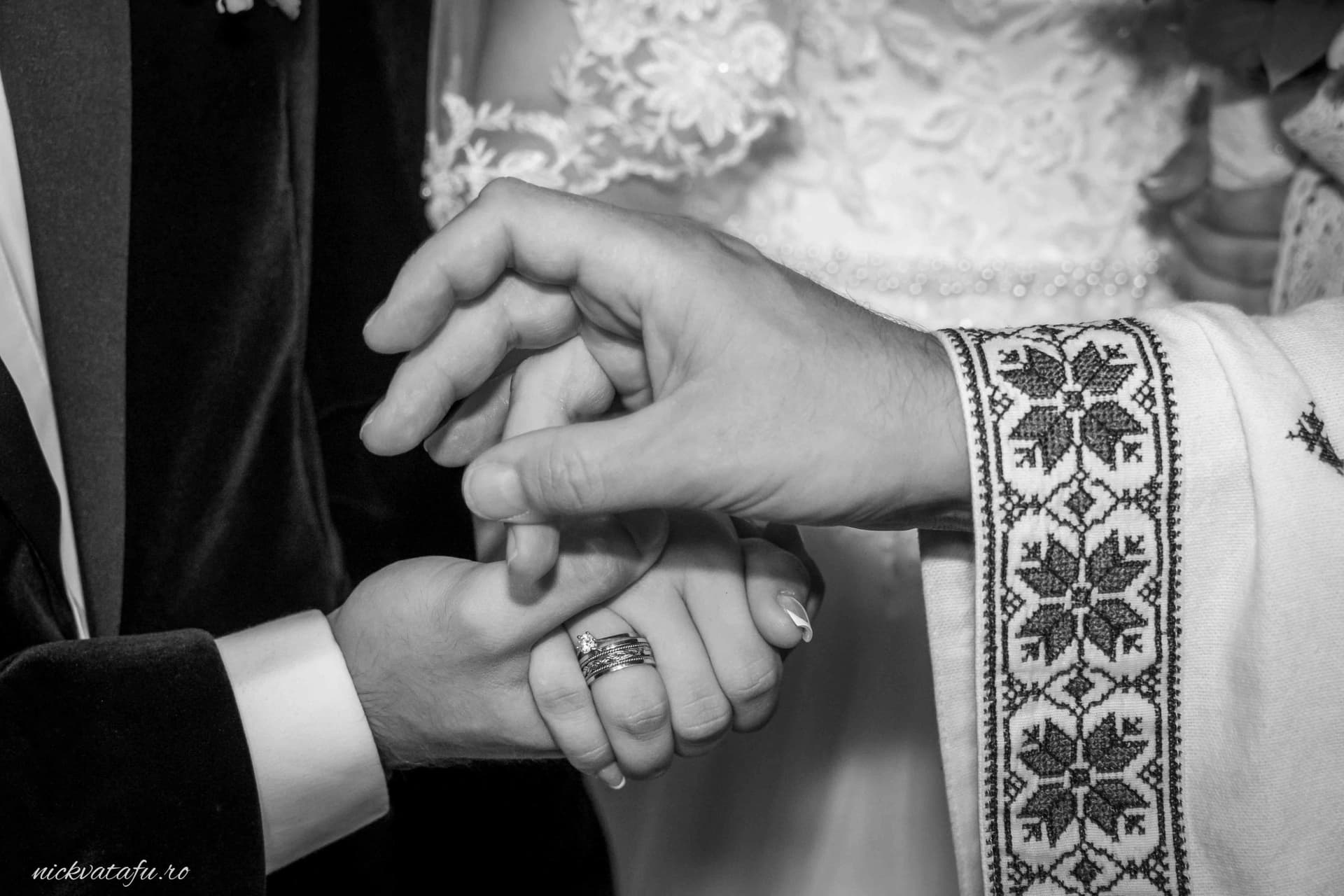 Mire și mireasă își țin mâinile unite, simbolizând dragostea și angajamentul în fotografia de nuntă.