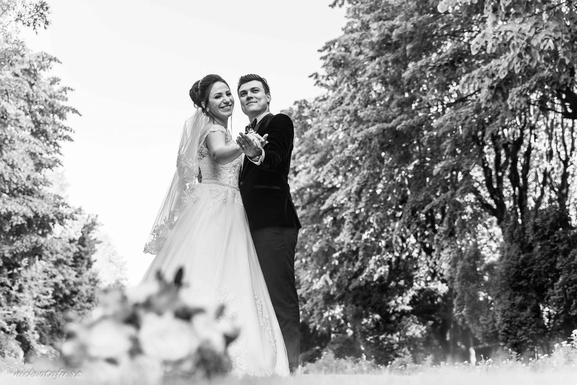 Mire și mireasă dansând fericiți într-un decor natural, fotografie de nuntă plină de emoție și eleganță.