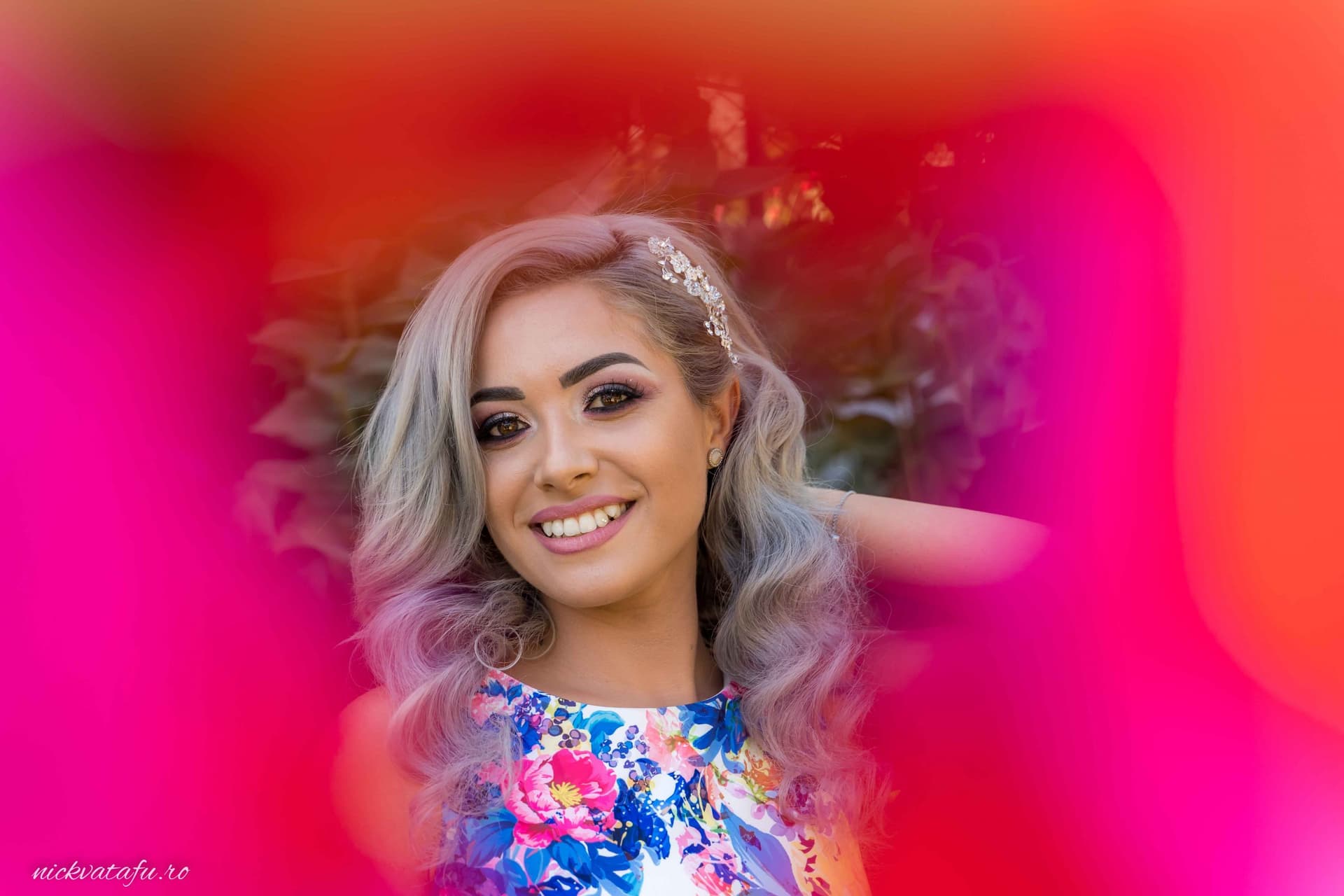 Tânără zâmbitoare cu părul ondulat și detalii florale, fotografie vibrantă, plină de emoție și culoare.