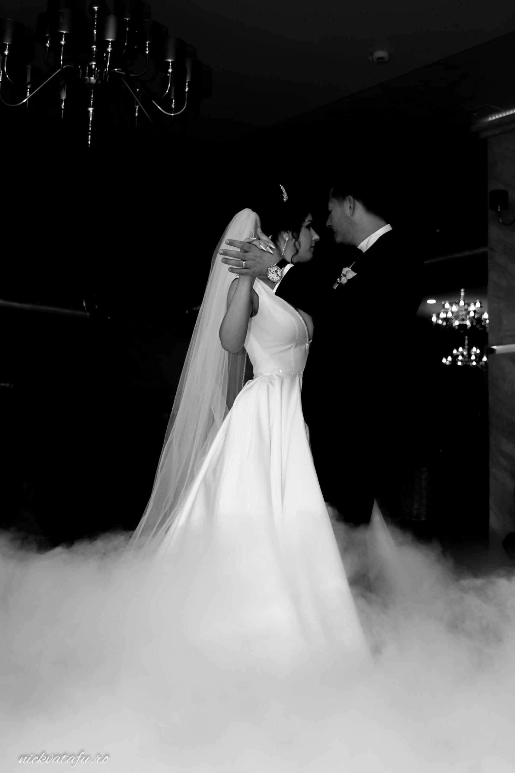 Mire și mireasă dansând într-o atmosferă romantică, învăluiți în ceață, fotografie de nuntă elegantă.