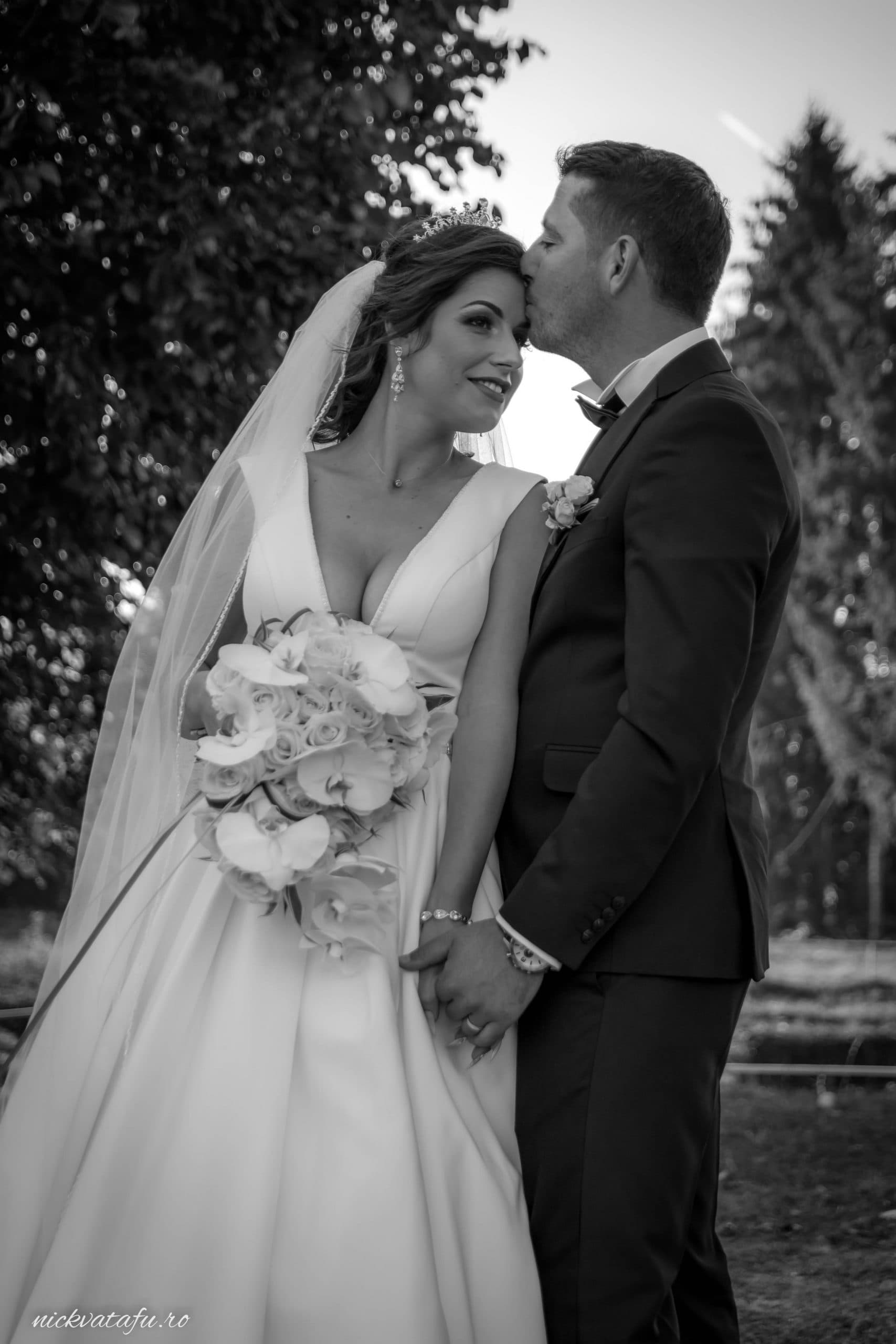 Mire și mireasă îmbrățișați, zâmbind fericiți, în mijlocul naturii, fotografie de nuntă plină de emoție.
