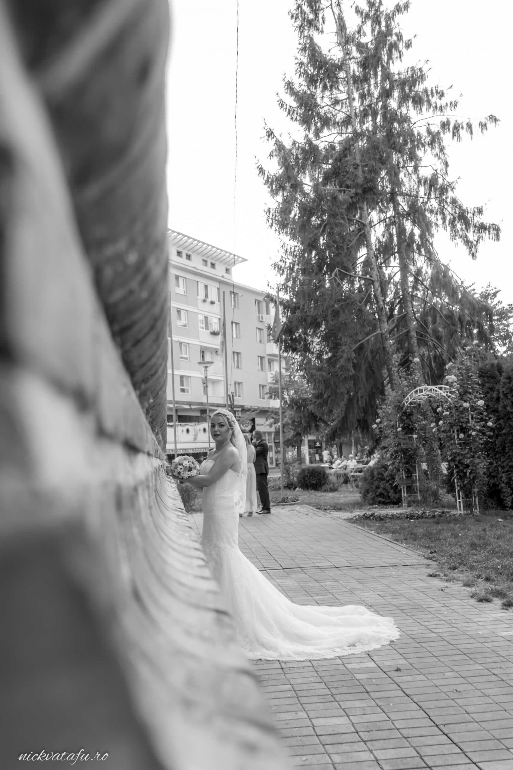 Mireasă elegantă în rochie albă, pozând emoționant într-un parc, fotografie de nuntă în Pitești.