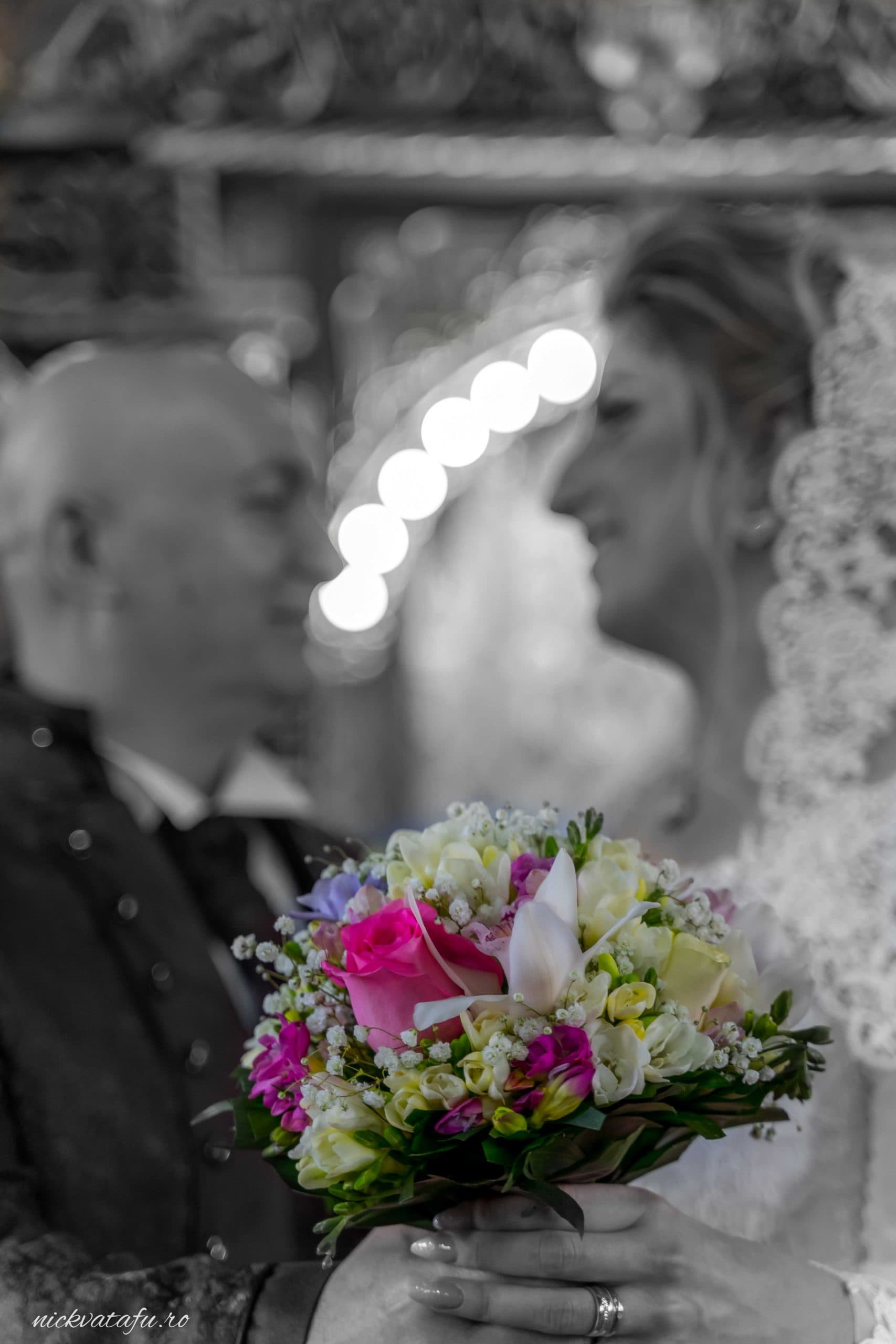 Mire și mireasă admirându-se cu emoție, cu buchet de flori în prim-plan, fotografie de nuntă plină de detalii.