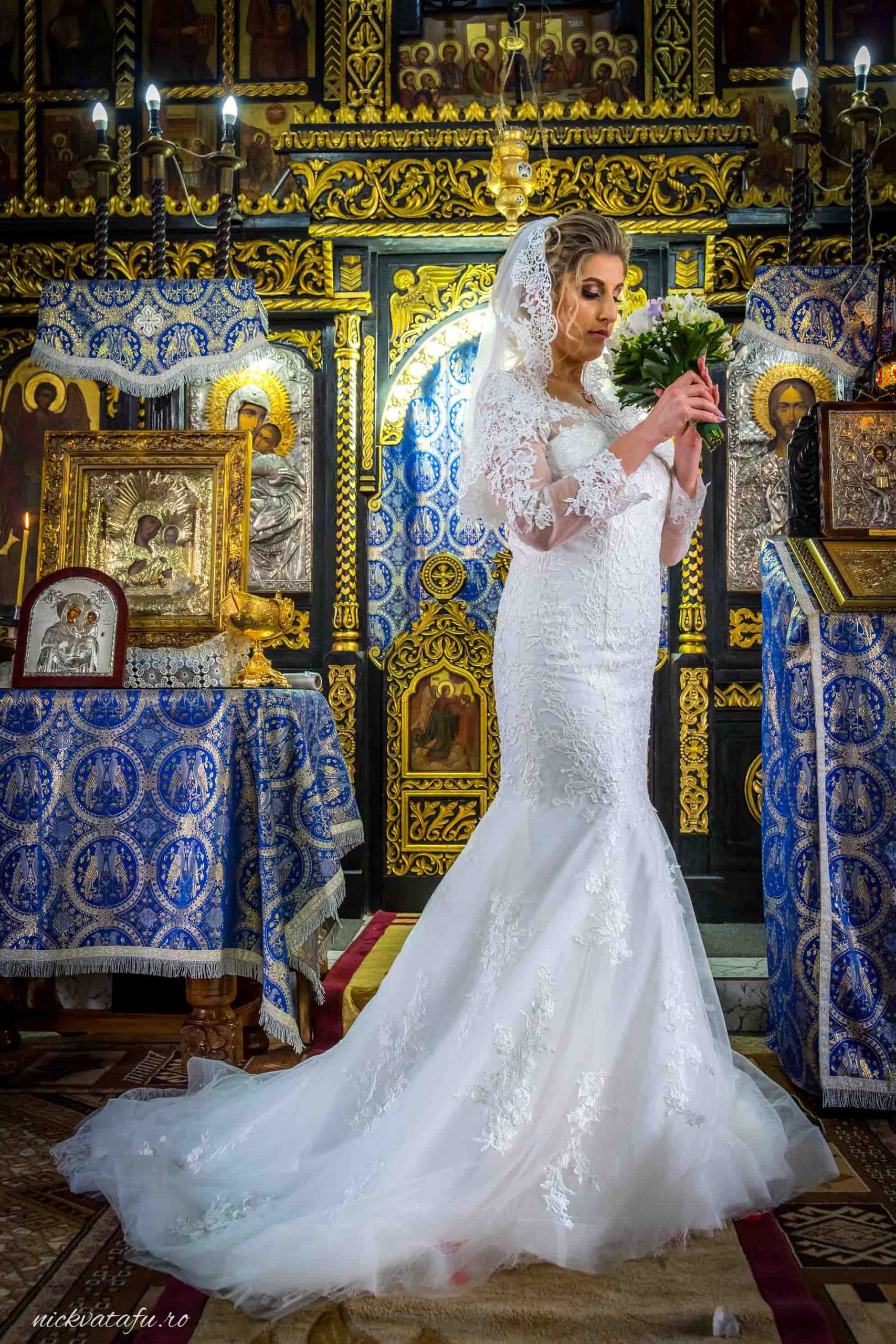 Mireasă elegantă în rochie albă, pregătindu-se pentru ceremonie într-o biserică decorată, fotografie de nuntă plină de emoție.