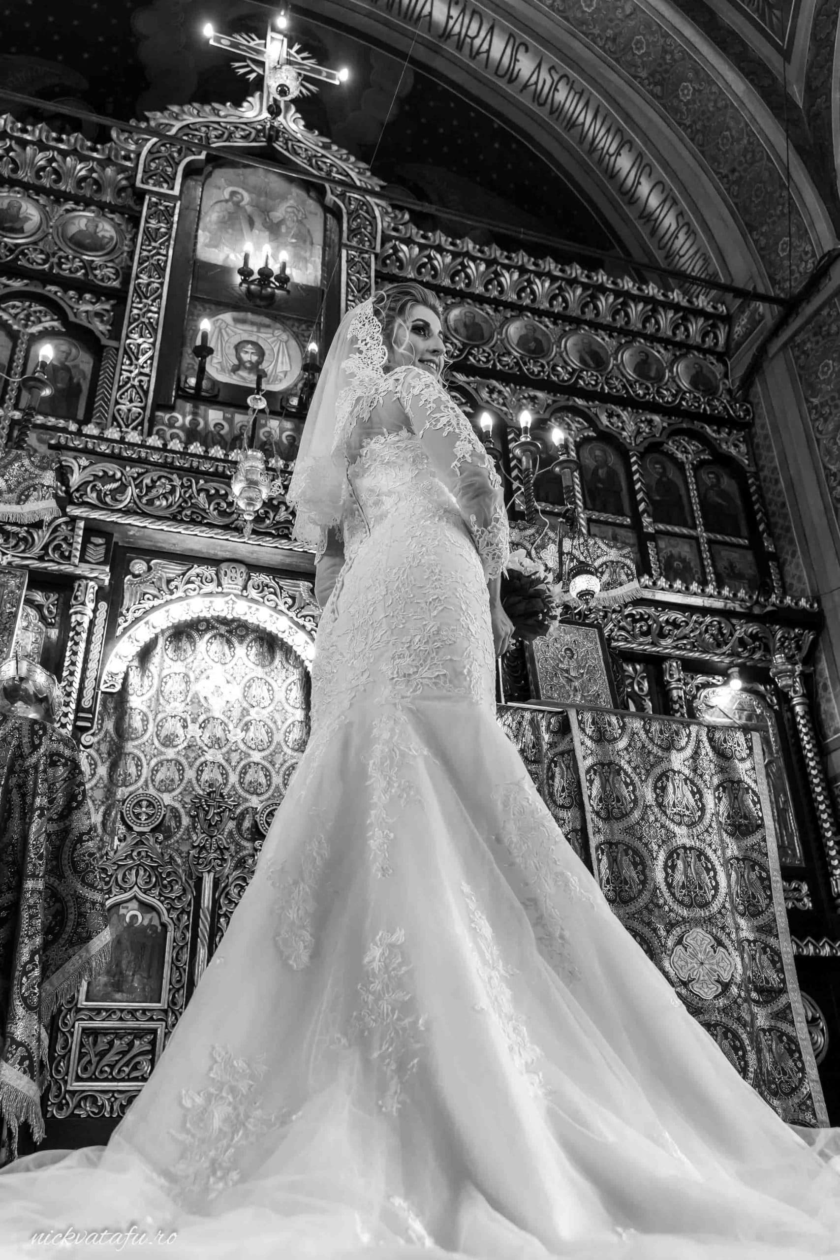 Mireasă elegantă într-o rochie de nuntă, surprinsă în biserică, emanând emoție și solemnitate.