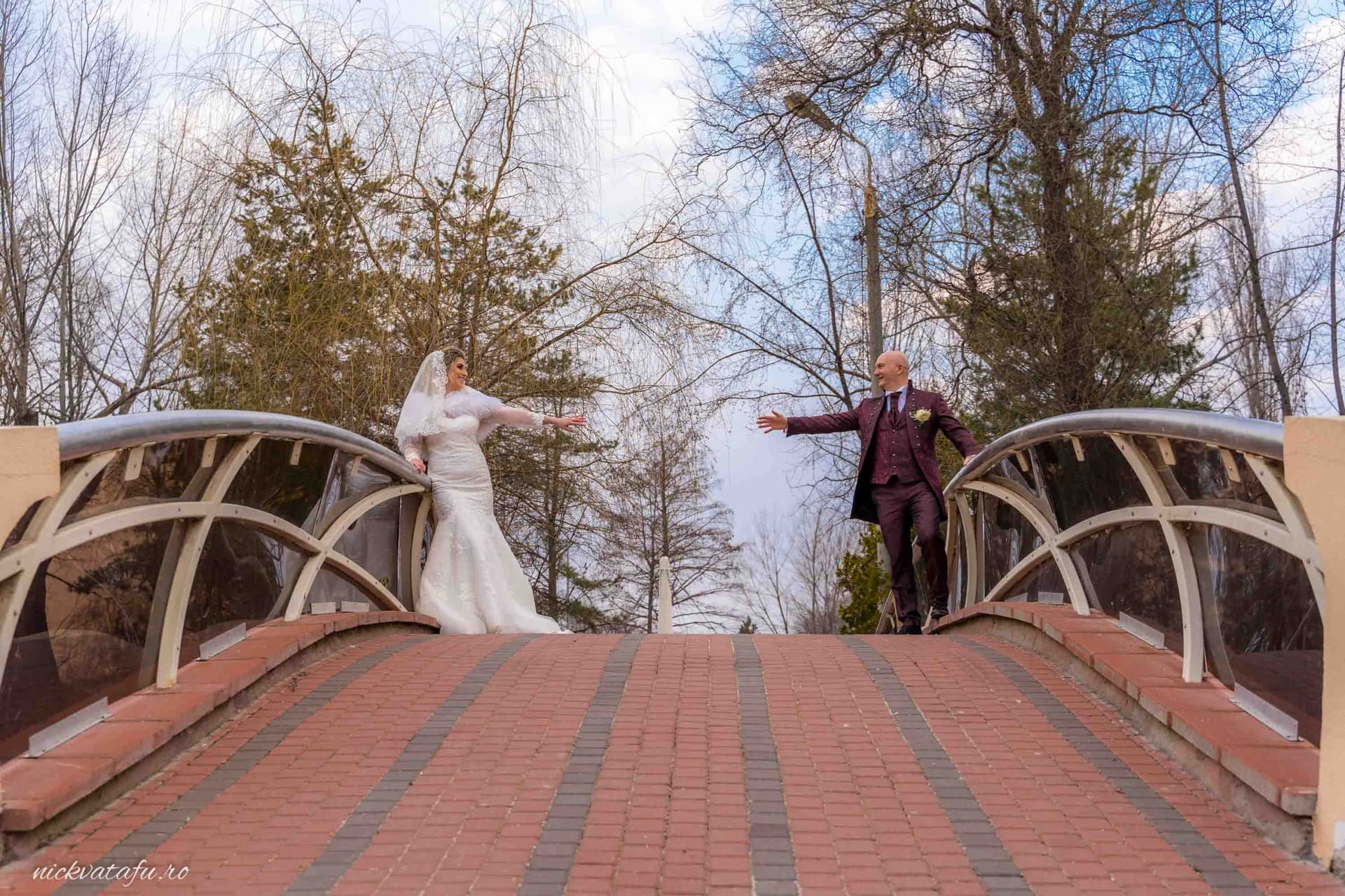 Mire și mireasă pe un pod, îndreptându-se unul spre altul, plini de emoție într-o fotografie de nuntă romantică.