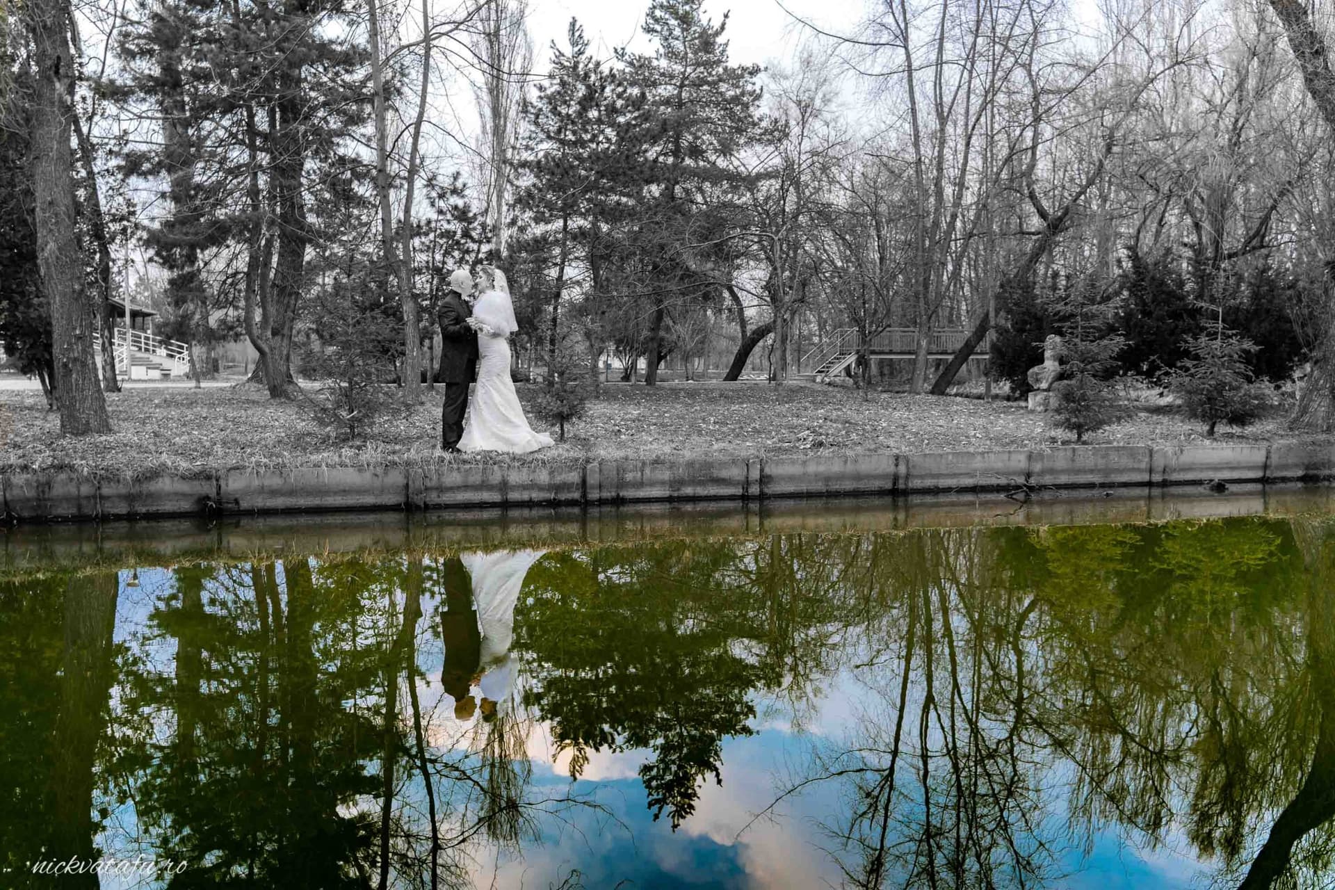 Mire și mireasă pe malul unui lac, înconjurați de natură, fotografie de nuntă plină de emoție și romantism.