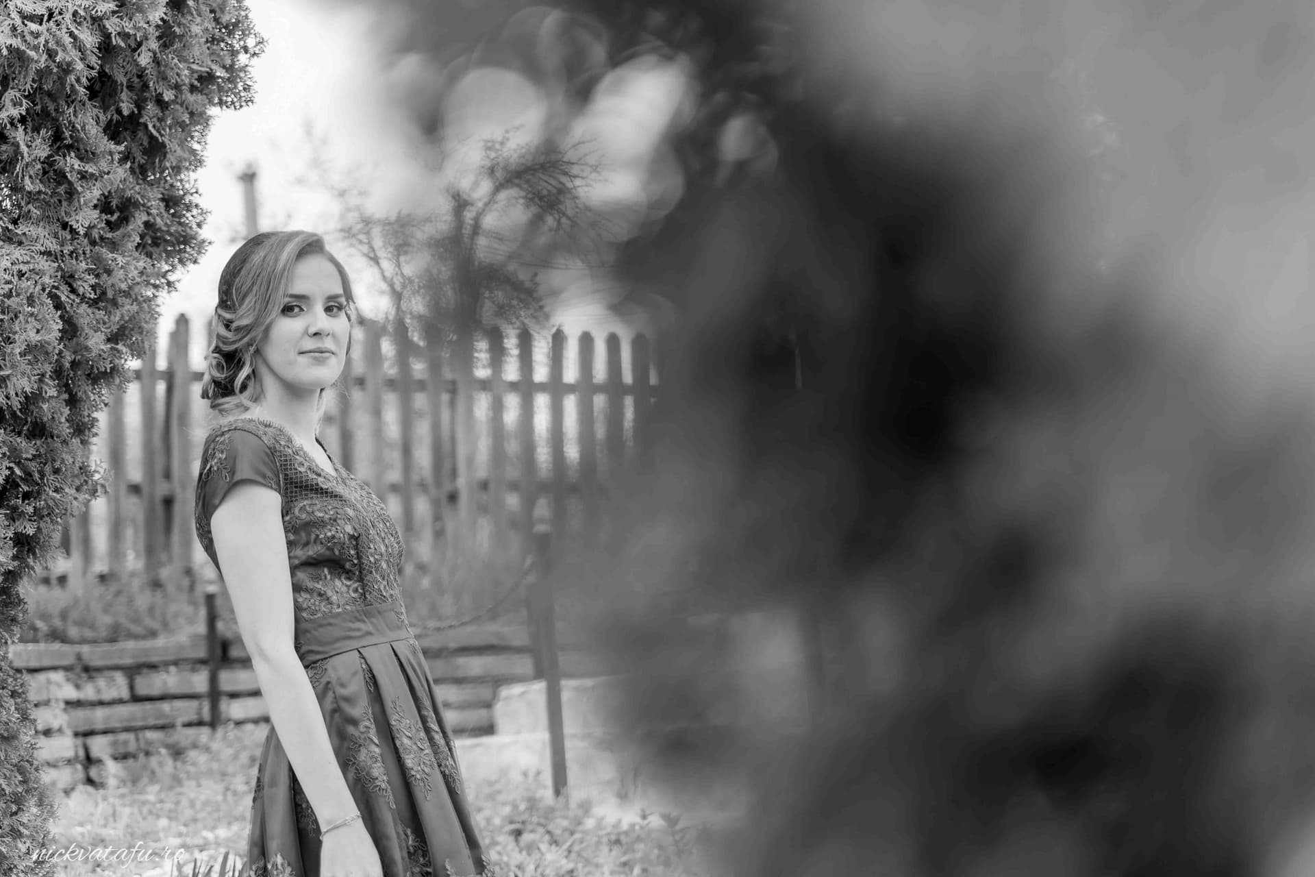 Fată elegantă, zâmbitoare, în rochie, surprinsă într-un cadru natural, fotografie de nuntă ce emană emoție.