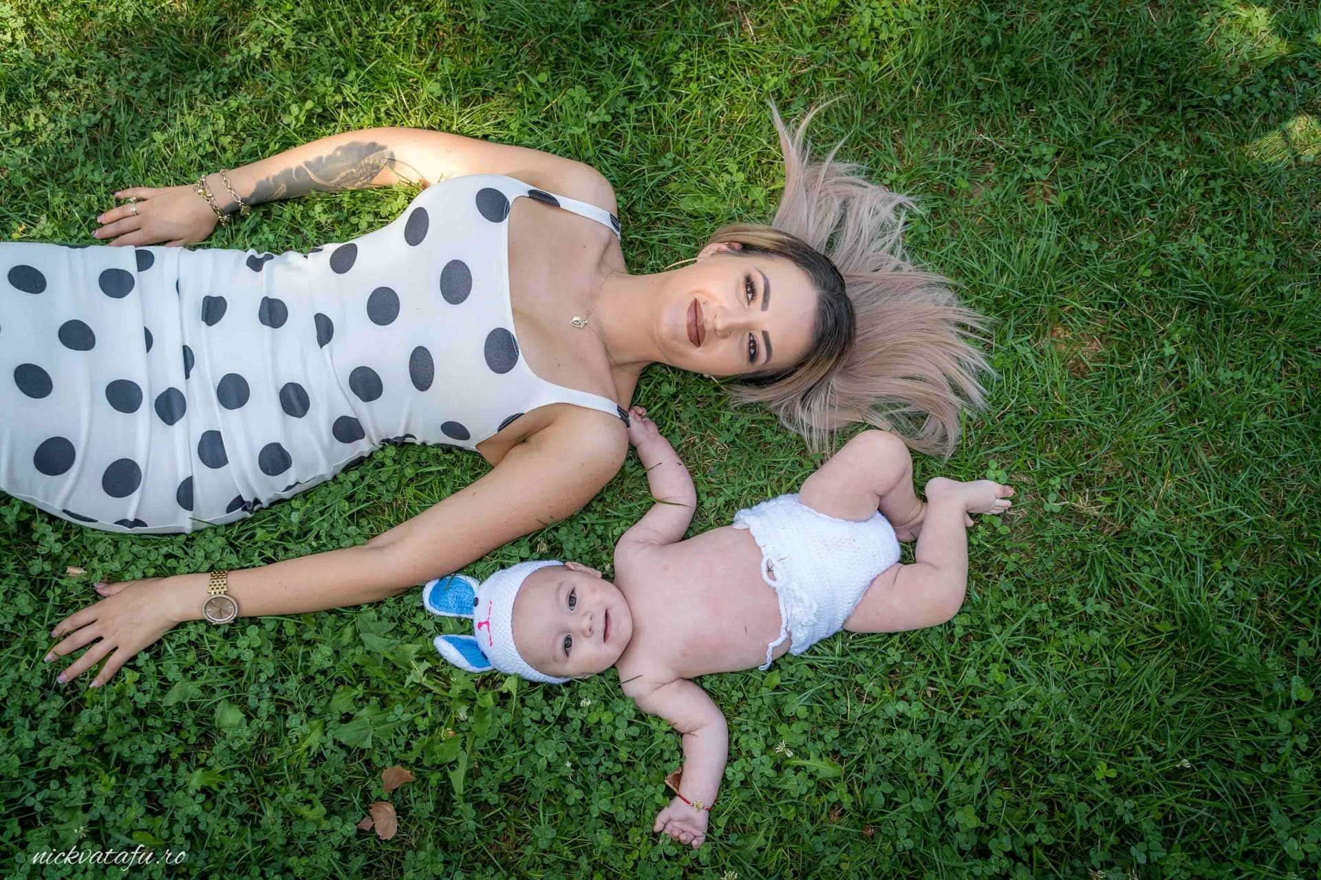 Mamă și copil zâmbind pe iarbă, surprinși într-un moment de joacă, fotografie emoționantă de familie.
