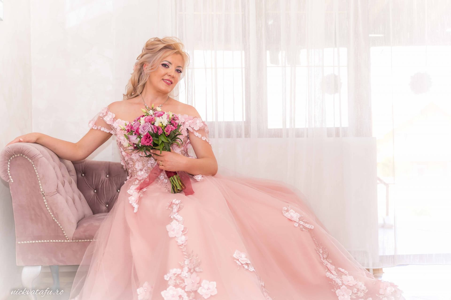 Mireasă elegantă, zâmbind cu un buchet de flori, într-o fotografie de nuntă, surprinsă într-un decor luminos.