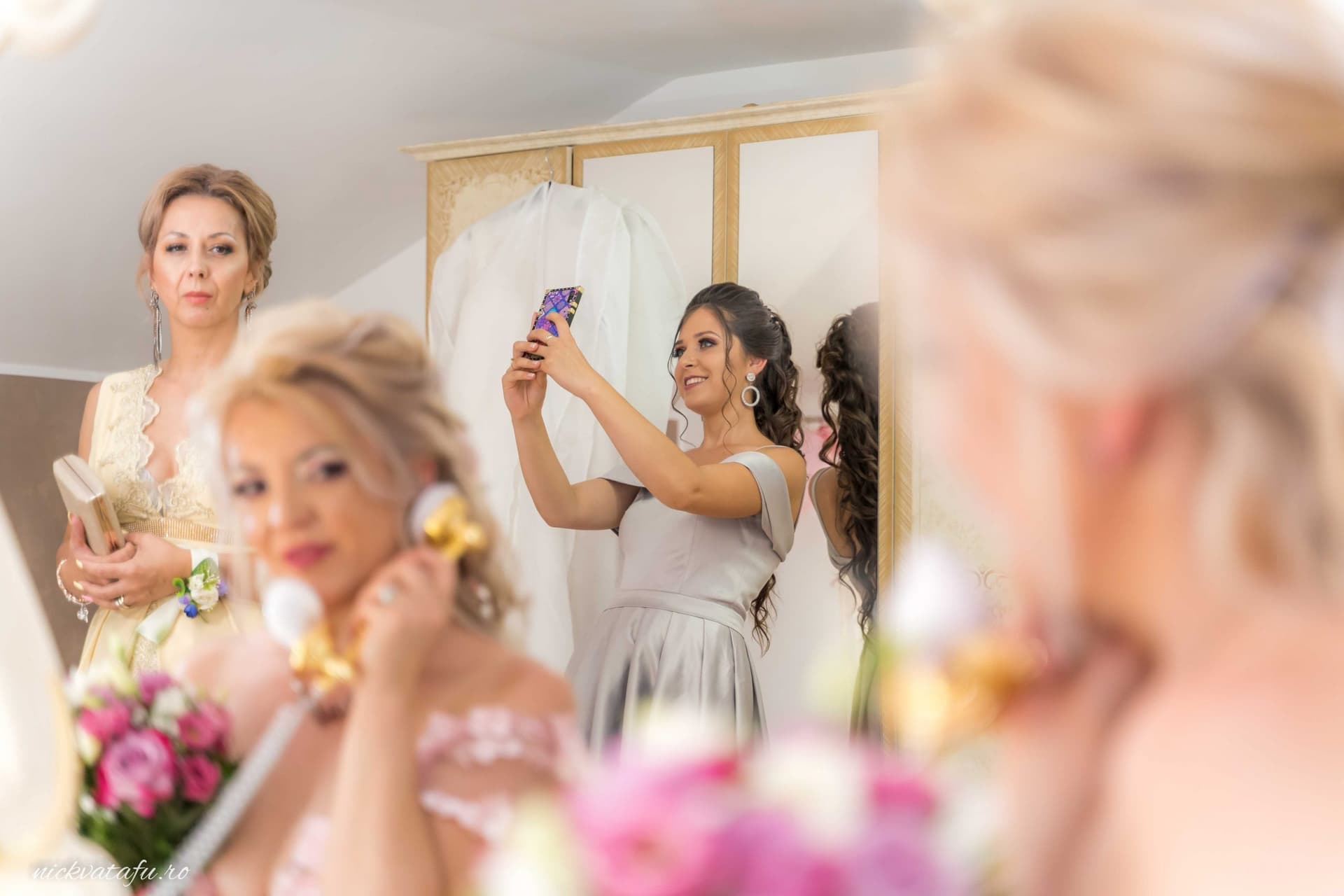 Mireasă și domnițe de onoare pregătindu-se, surprinse într-un moment plin de emoție și bucurie înainte de ceremonie.