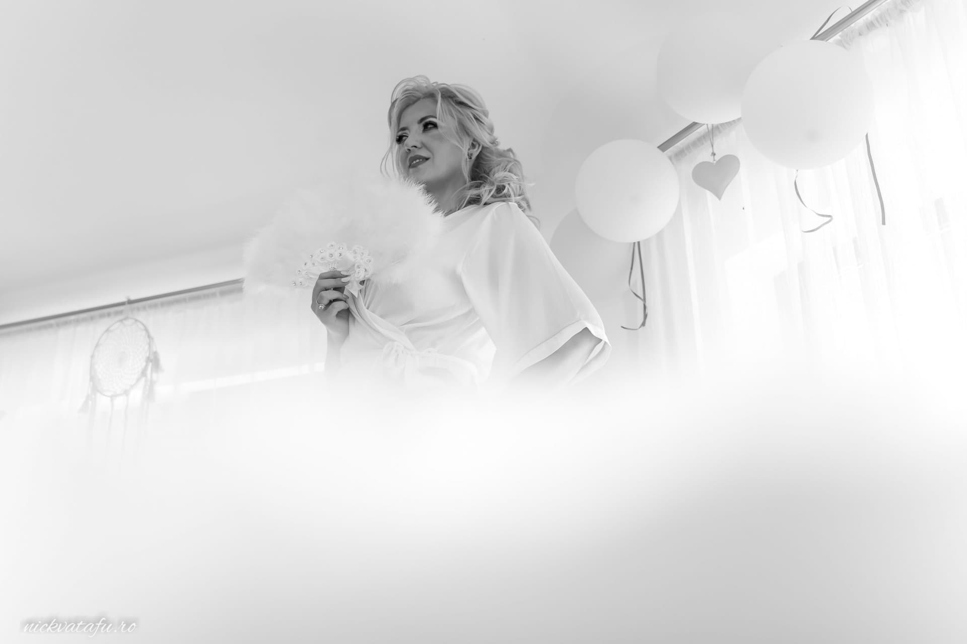 Mireasă zâmbitoare cu evantai, surprinsă în detalii elegante, fotografie de nuntă plină de emoție.