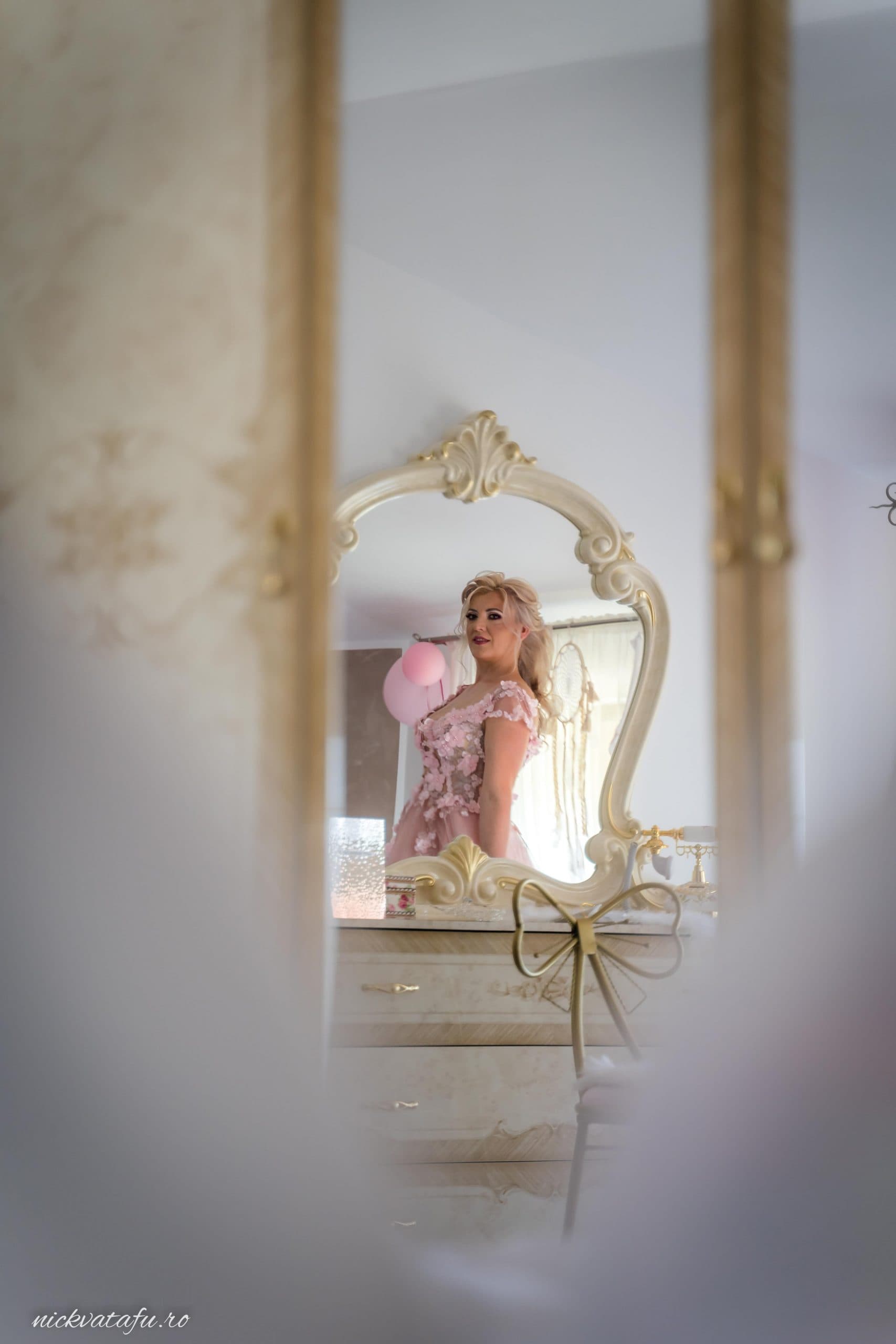 Mireasă elegantă admirându-se în oglindă, detalii delicate de nuntă și emoție în atmosfera pregătirilor.