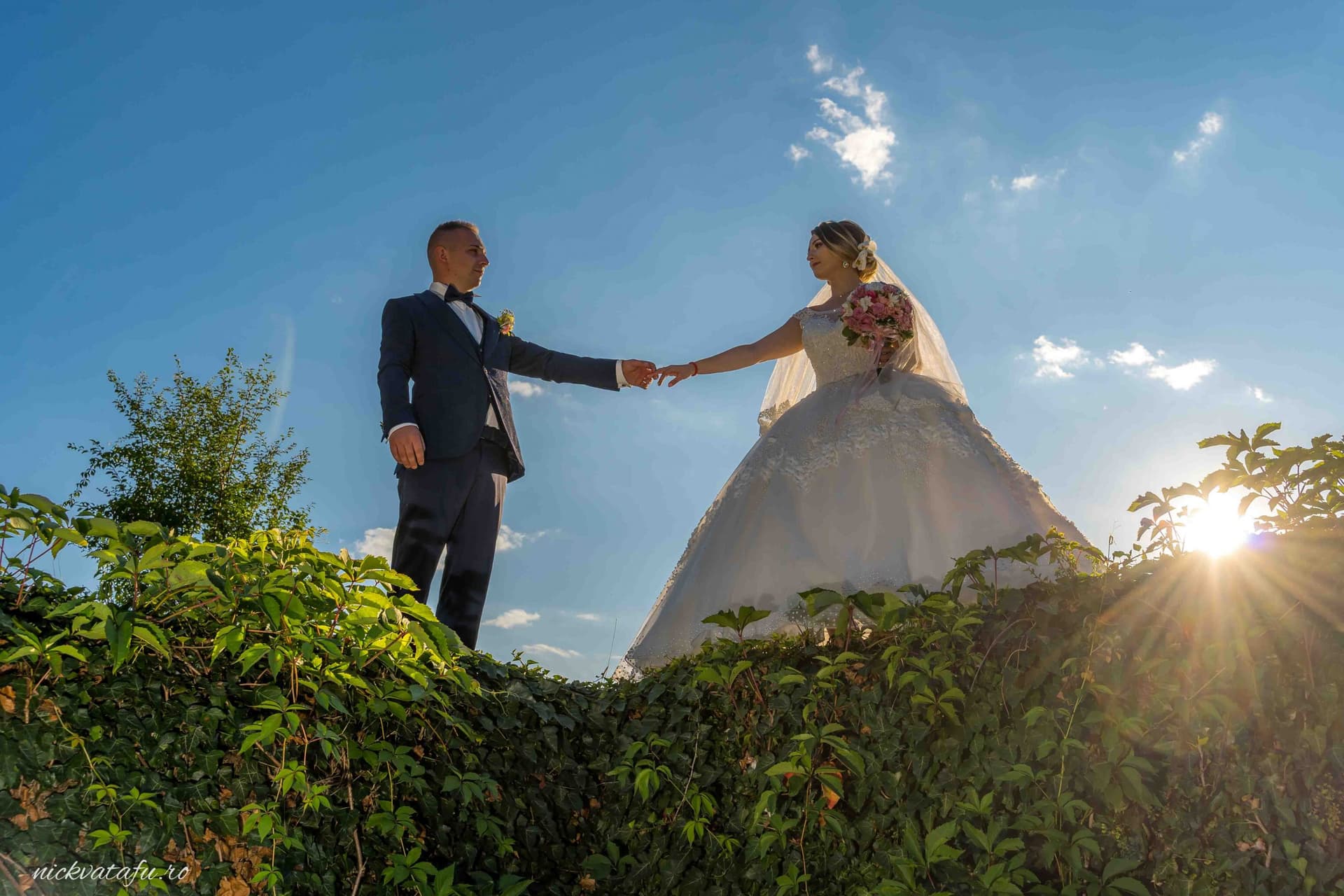 Mire și mireasă ținându-se de mână, într-un peisaj natural, fotografie de nuntă plină de emoție și iubire.