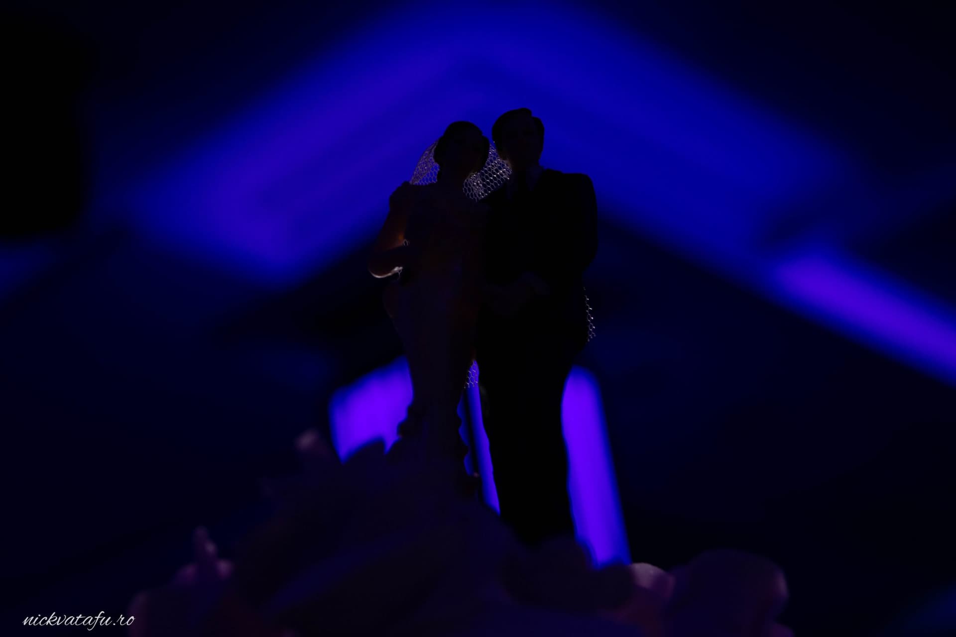 Mire și mireasă în umbra luminii violet, emoție intensă la o fotografie de nuntă.