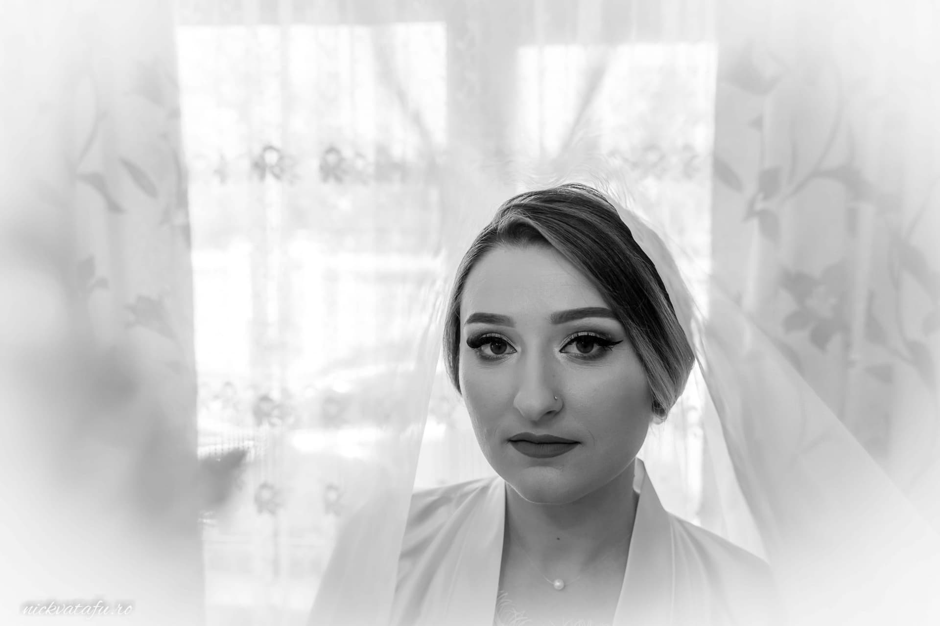Mireasă contemplativă cu voal, surprinsă în lumina naturală, fotografie elegantă de nuntă.