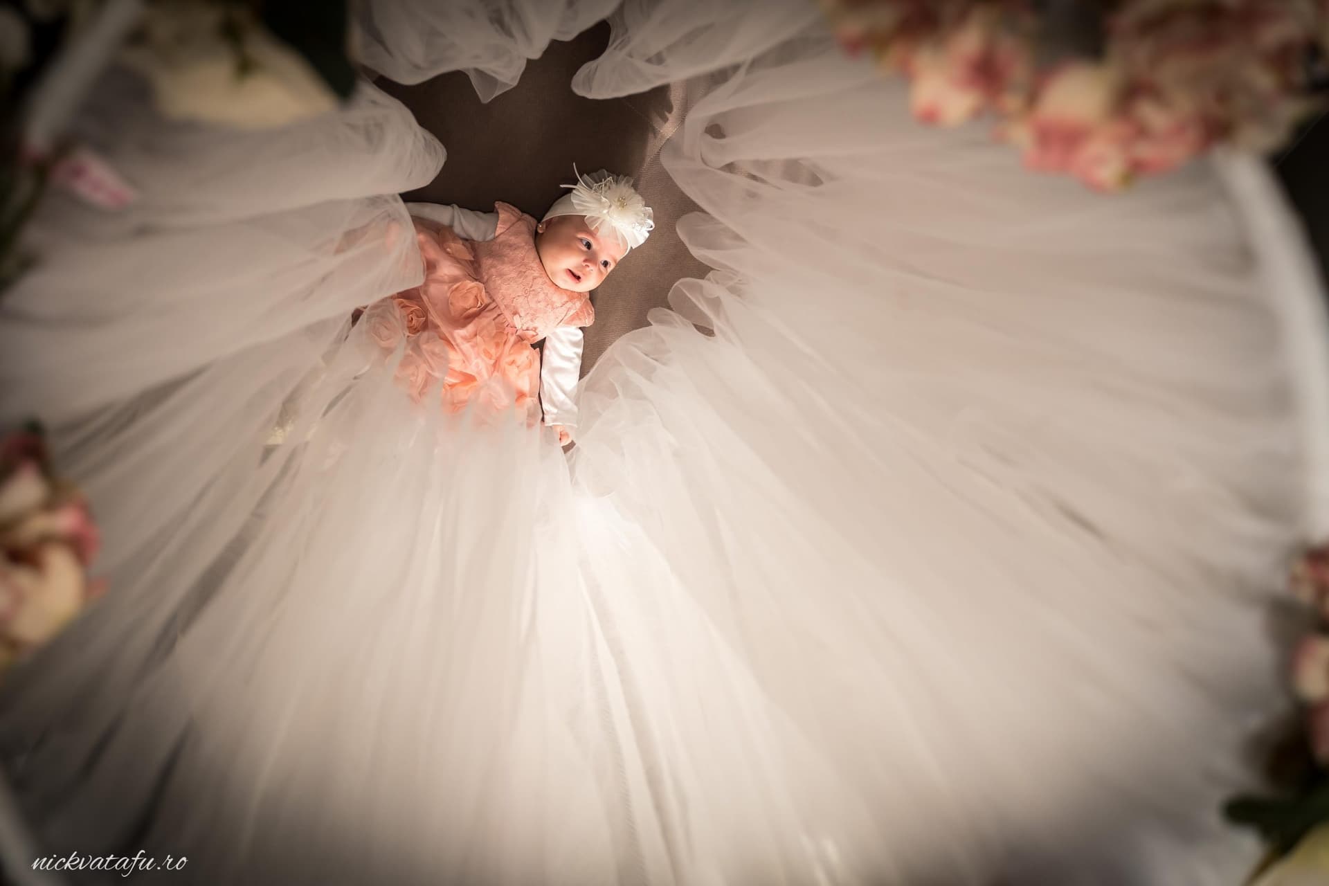 Fetiță purtând o rochie elegantă de mireasă, înconjurată de voaluri delicate, emanând bucurie și emoție.