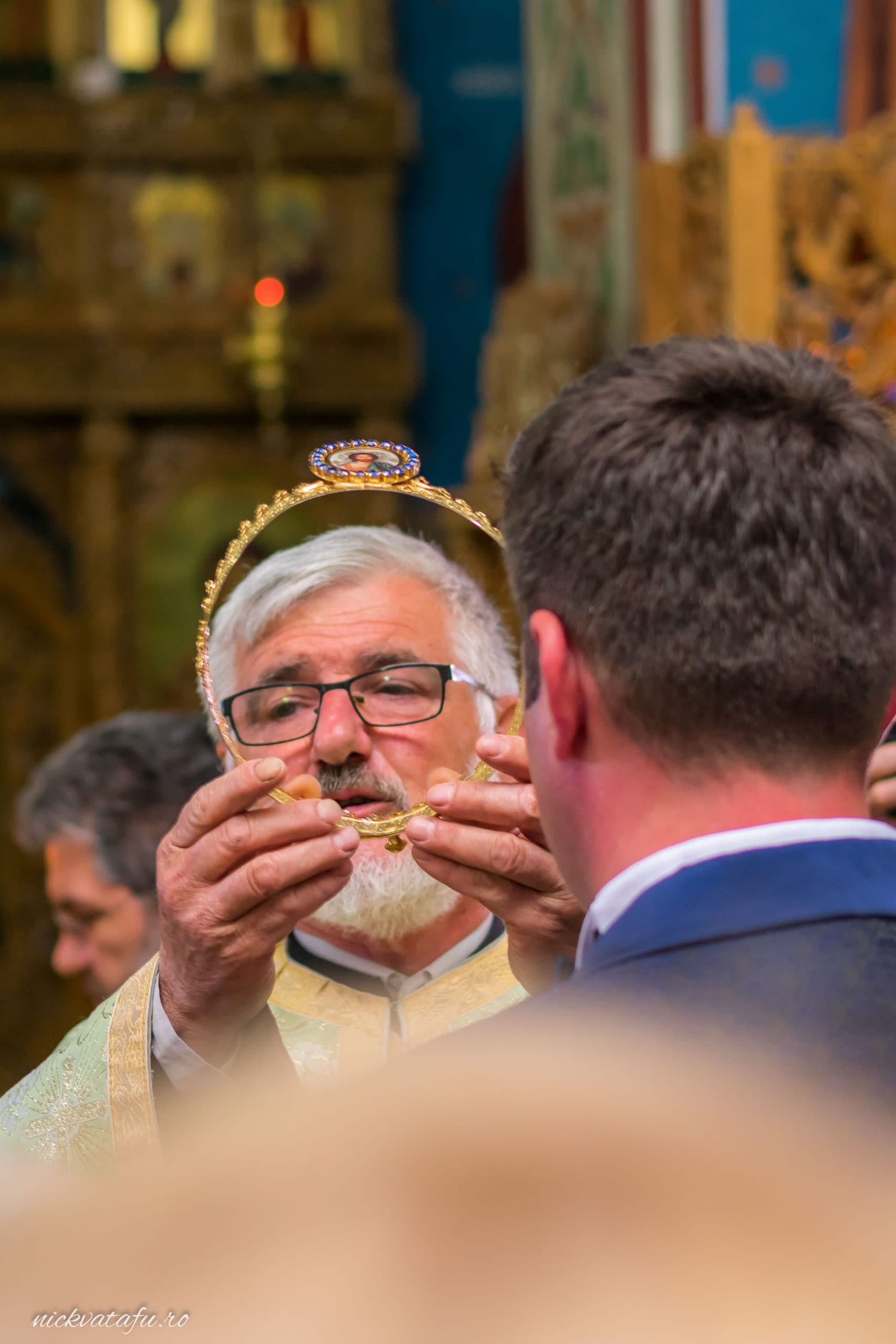 Preot binecuvântează verighetele în timpul ceremoniei de nuntă, emoție și solemnitate în aer.