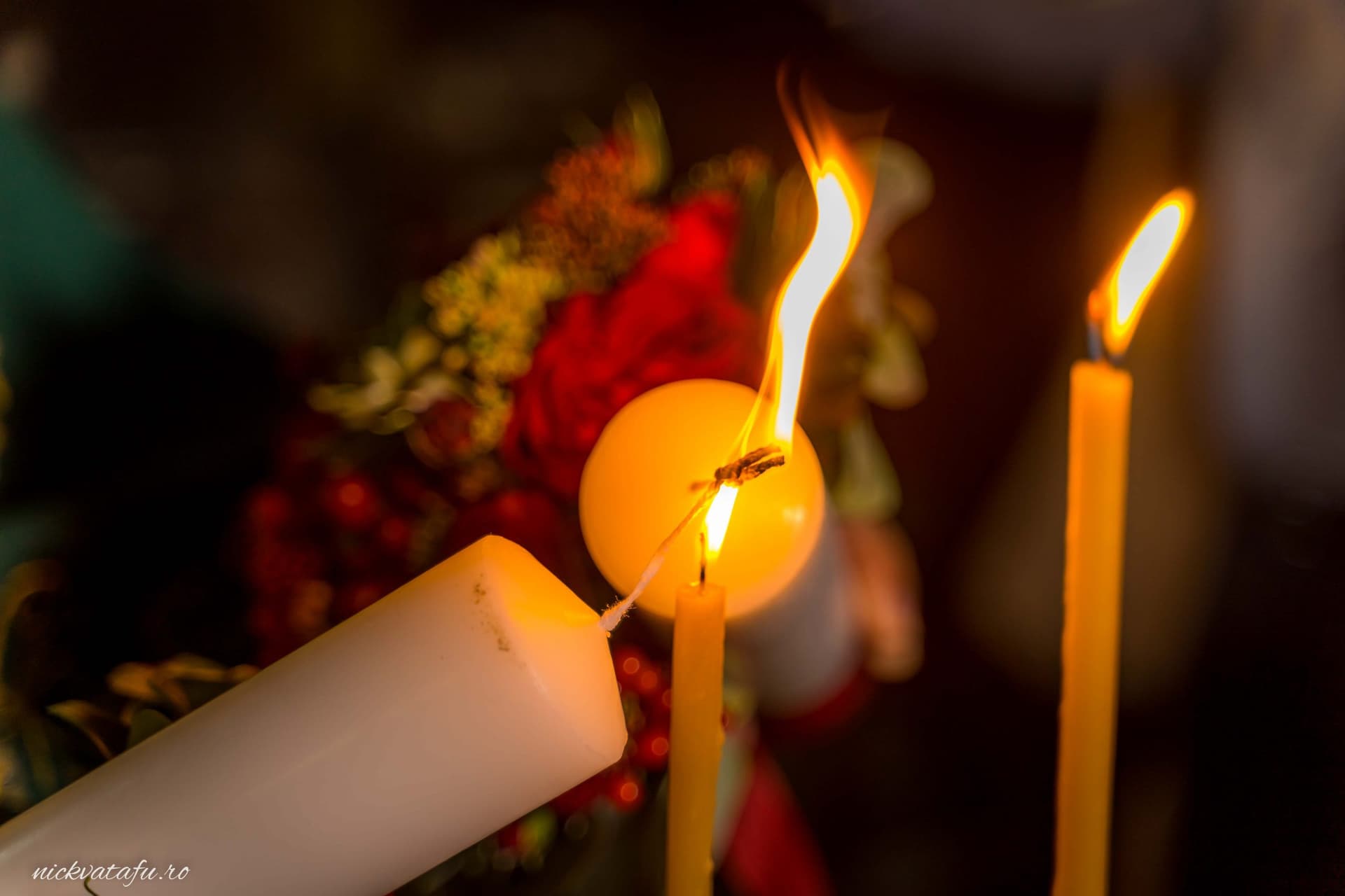 Candele aprinse, simbolizând emoția unei ceremonii de nuntă, detalii luminoase și calde într-un decor elegant.