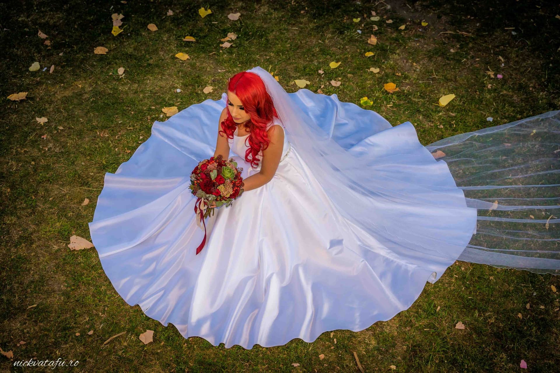 Mireasă cu rochie albă și buchet, așezată pe iarbă, emanând emoție și eleganță în fotografie de nuntă.