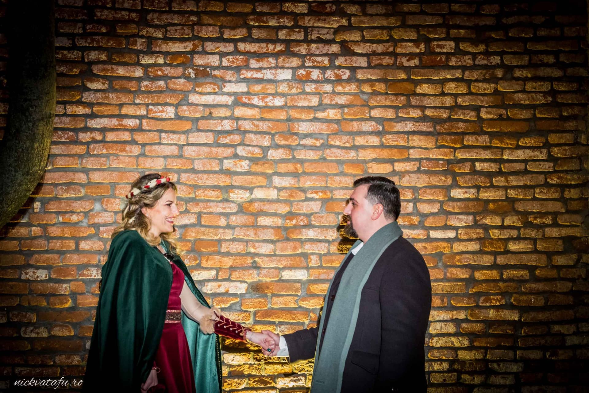 Mire și mireasă îmbrățișați, emoție intensă în fața unui zid de cărămidă, fotografie de nuntă elegantă.