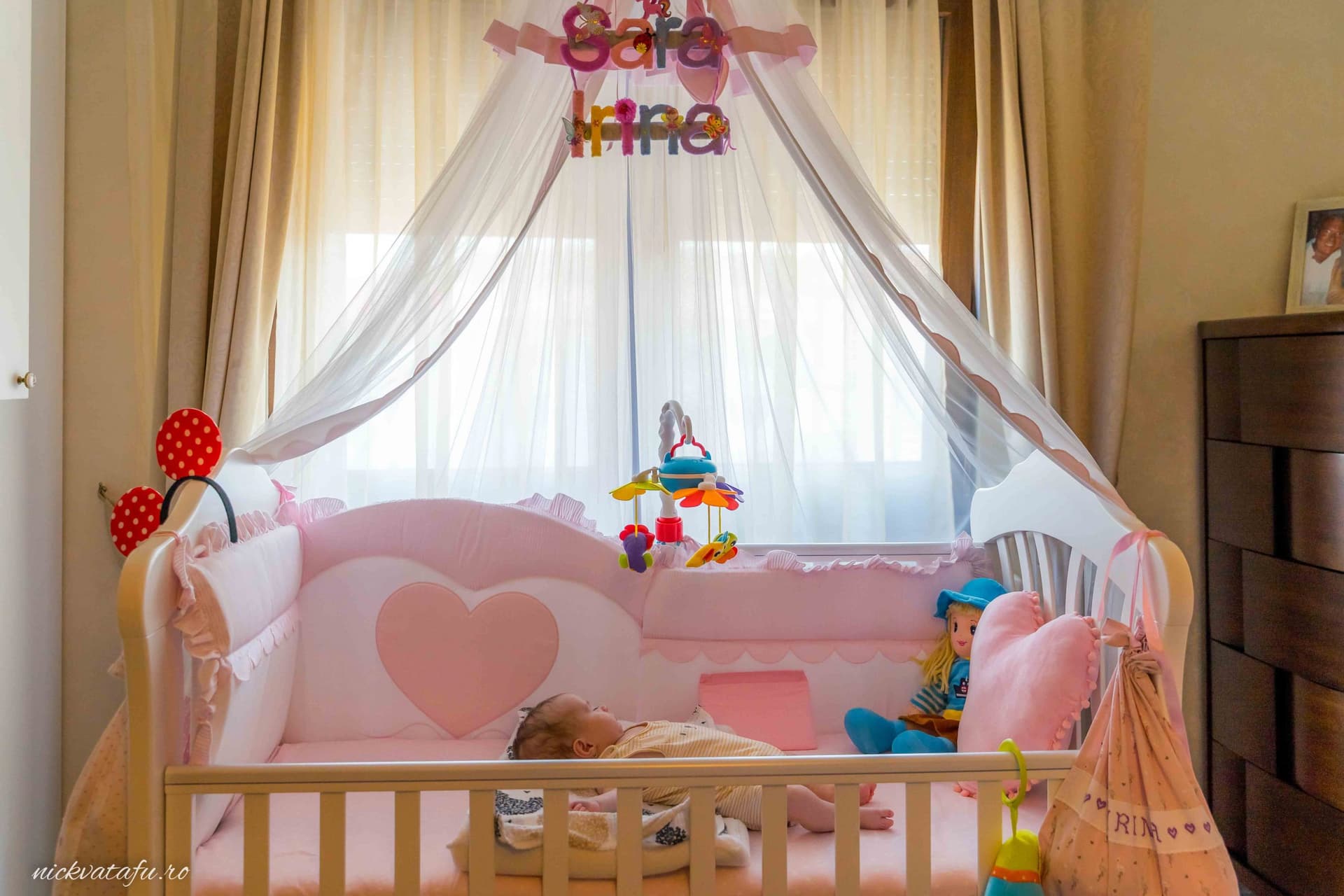 Patut roz cu detalii adorabile și jucării, evocând emoția unui botez în Pitești, cu un bebeluș somnoros.