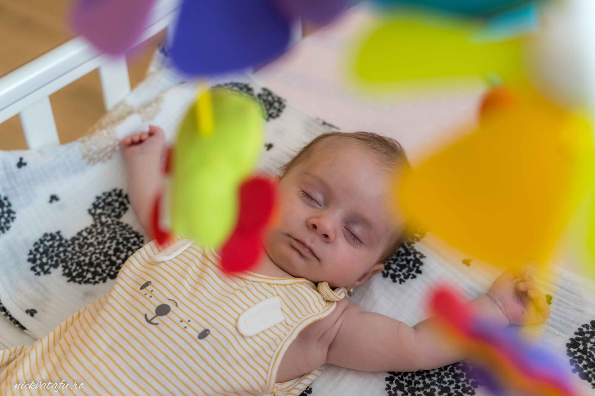 Bebeluș adormit, înconjurat de jucării colorate, evocând emoție și liniște, perfect pentru un botez Pitești.