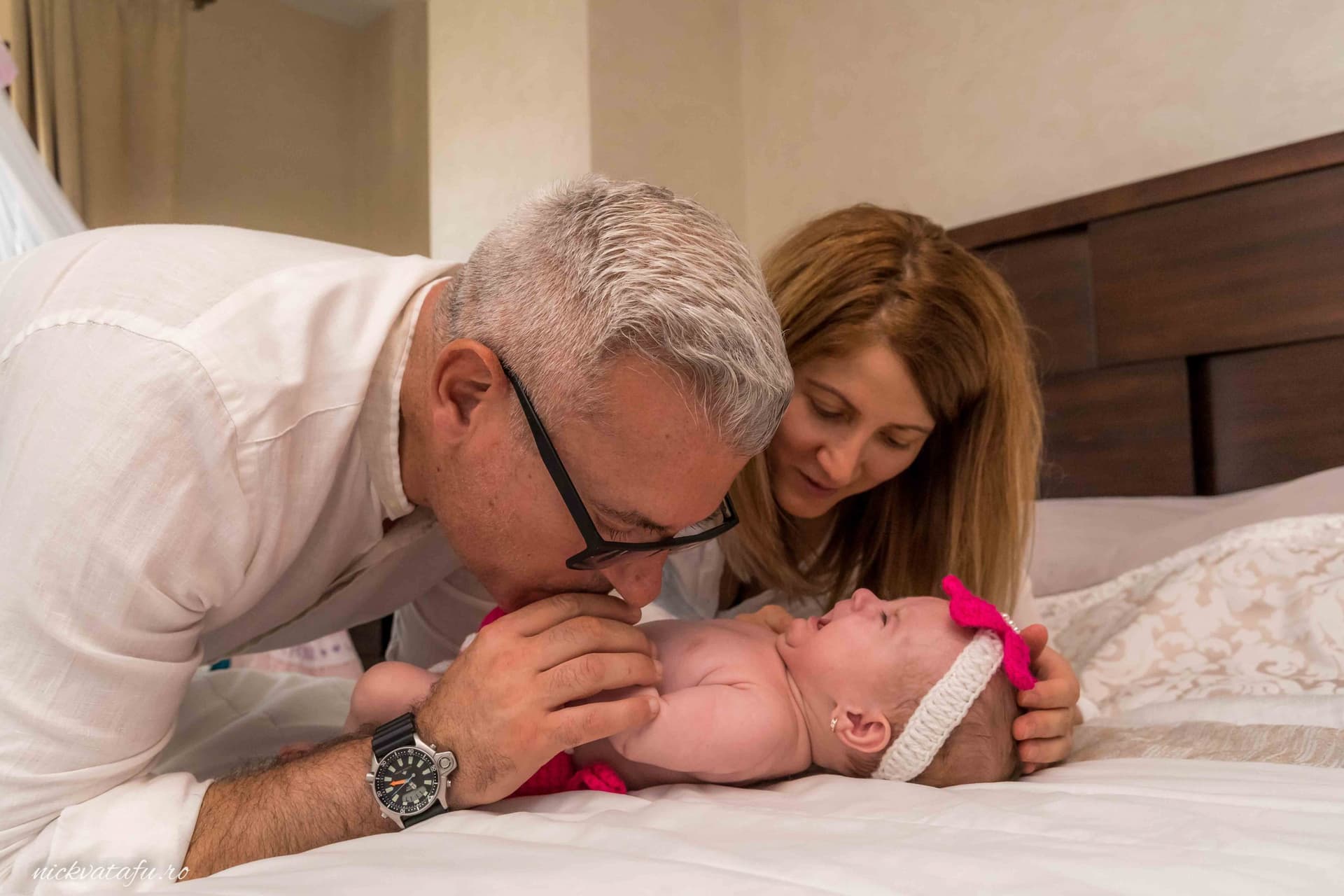 Bunici jucându-se cu nepoțica pe pat, emoție și iubire într-o fotografie de familie.
