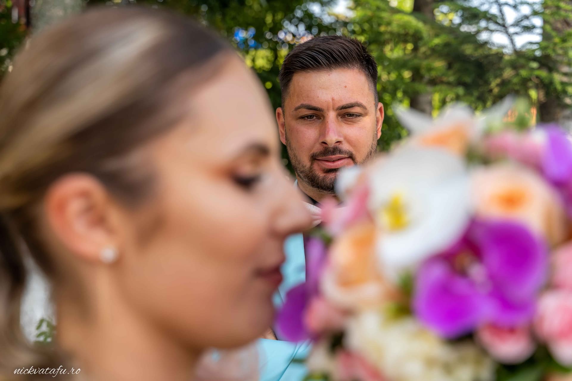 Mire și mireasă în prim-plan, cu emoții intense, fotografie de nuntă în aer liber, detalii florale vibrante.
