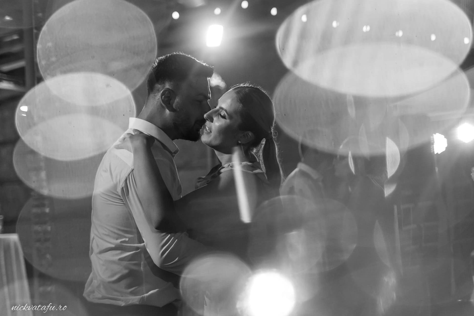 Mire și mireasă dansând pasional sub lumini strălucitoare, fotografie de nuntă plină de emoție și intimitate.