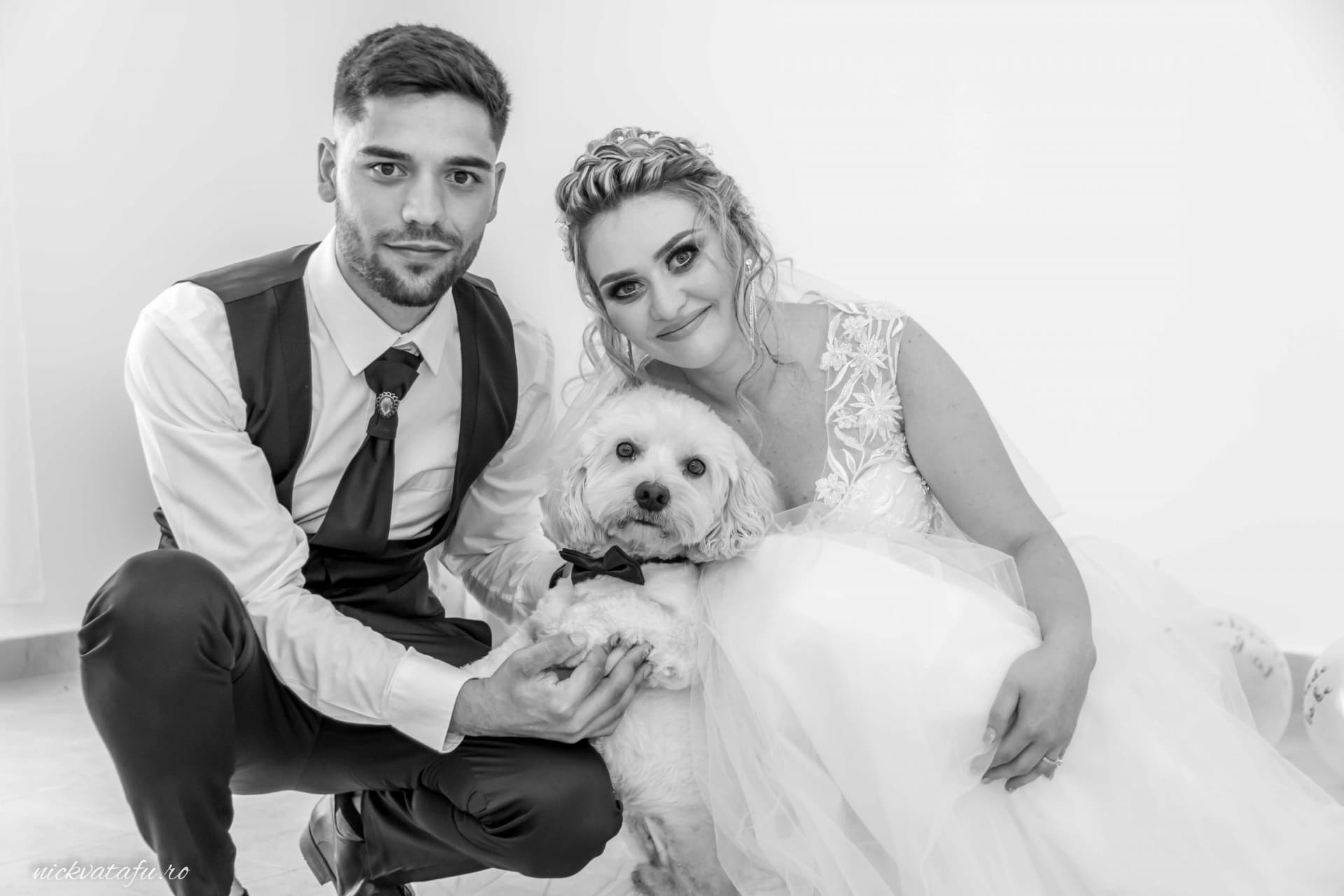 Mire și mireasă zâmbind fericiți, ținându-și câinele în brațe, fotografie nuntă plină de emoție.
