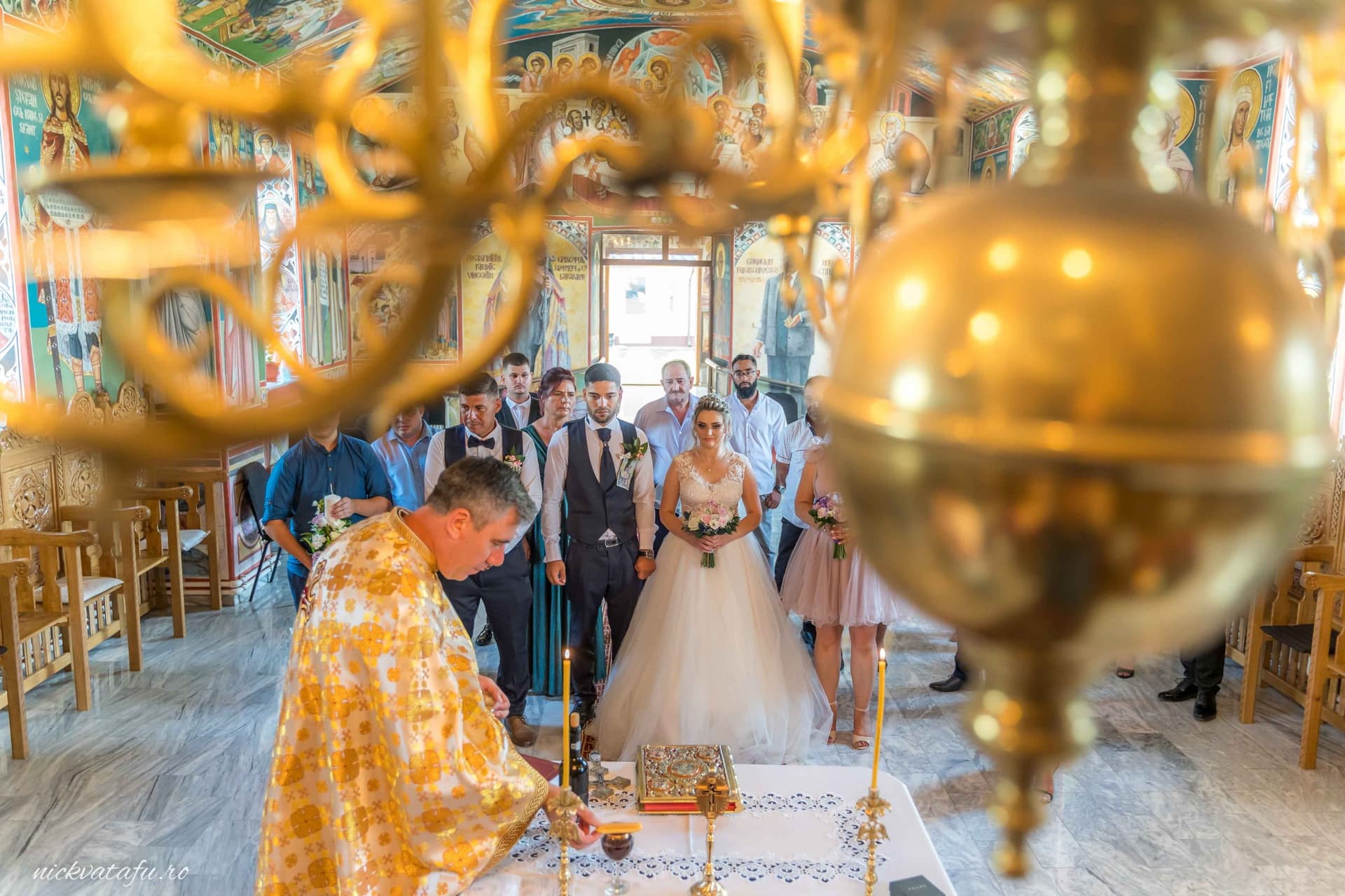 Ceremonie religioasă de nuntă cu mireasă și preot în prim-plan, emoție și detalii elegante în biserică.