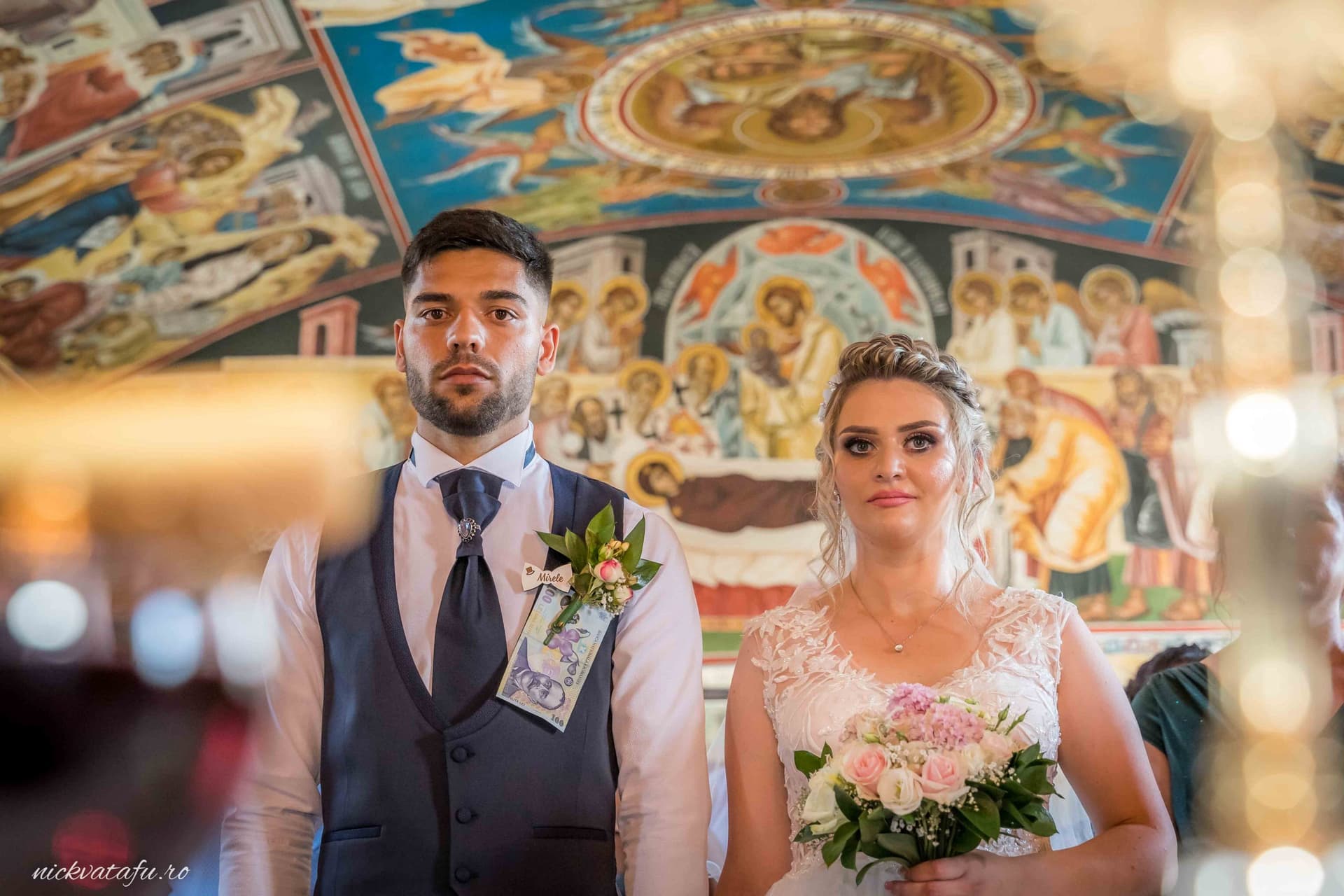 Mire și mireasă emoționați la ceremonie, cu detalii artistice în fundal, fotografie nuntă plină de bucurie.