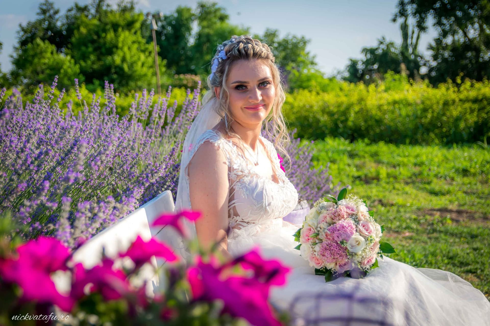 Mireasă zâmbitoare, înconjurată de flori colorate, într-o fotografie de nuntă plină de emoție și frumusețe naturală.