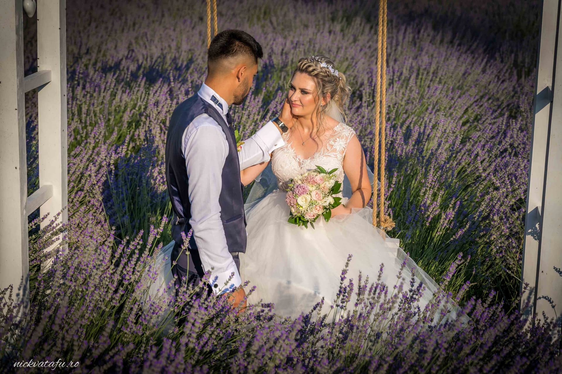 Mire și mireasă pe o leagăn în câmp de lavandă, emanând emoție și bucurie, fotografie de nuntă romantică.