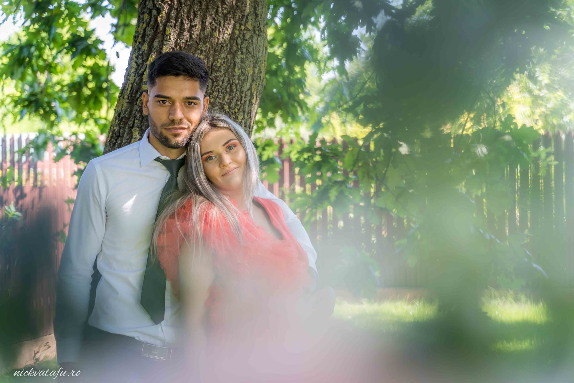 Cuplu îndrăgostit pozând lângă un copac, surprinși într-o atmosferă romantică, fotografie elegantă de nuntă.