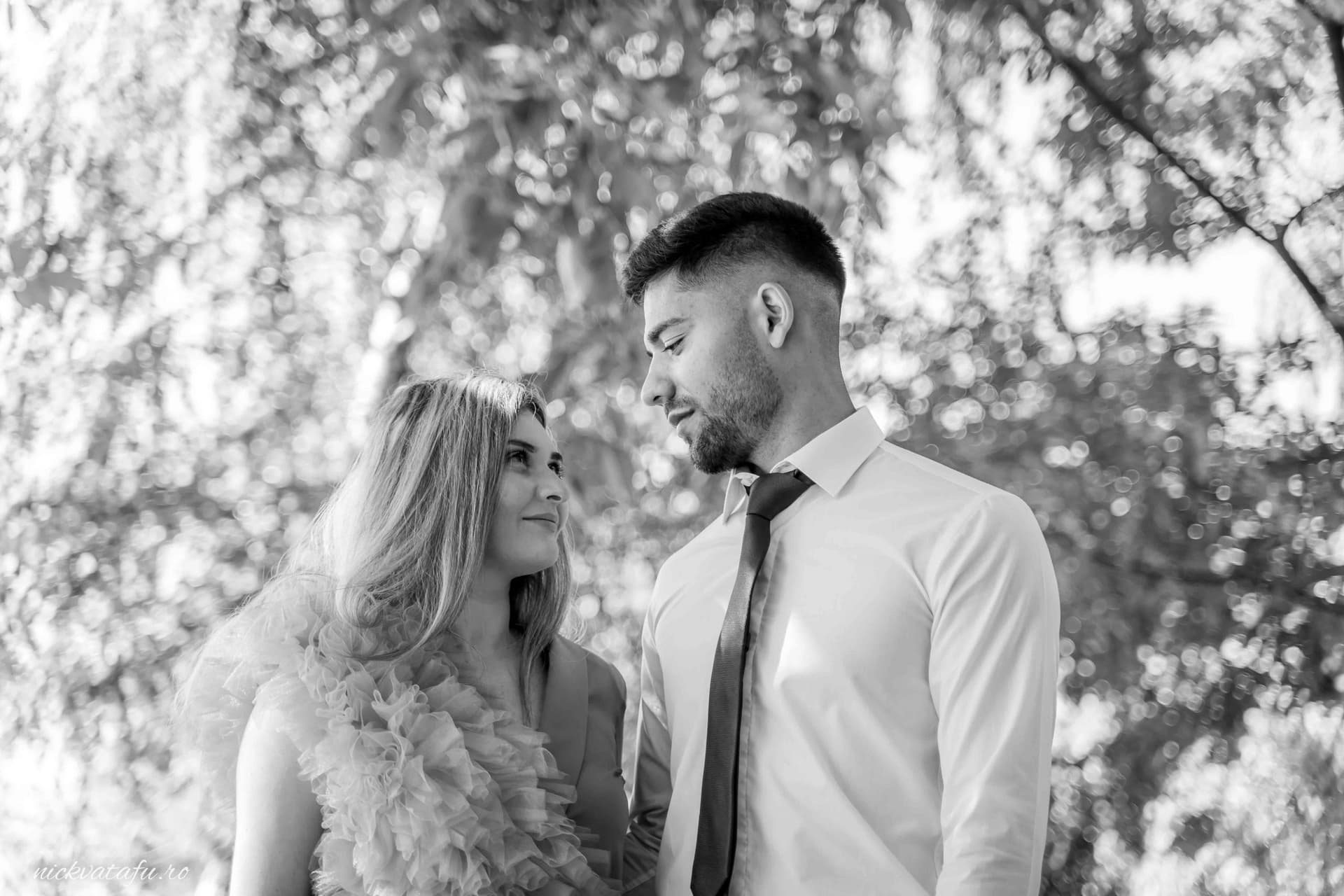 Cuplu îndrăgostit privindu-se cu intensitate, într-un cadru natural, fotografie nuntă plină de emoție.