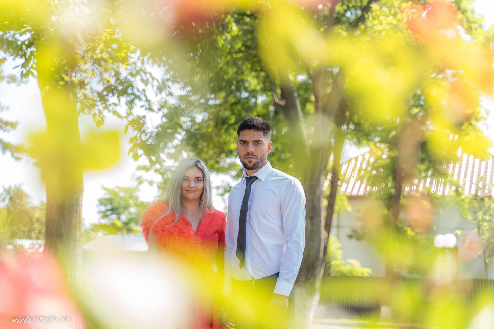 Cuplu elegant în natură, surprinși în moment de intimitate, fotografie de nuntă cu detalii romantice.