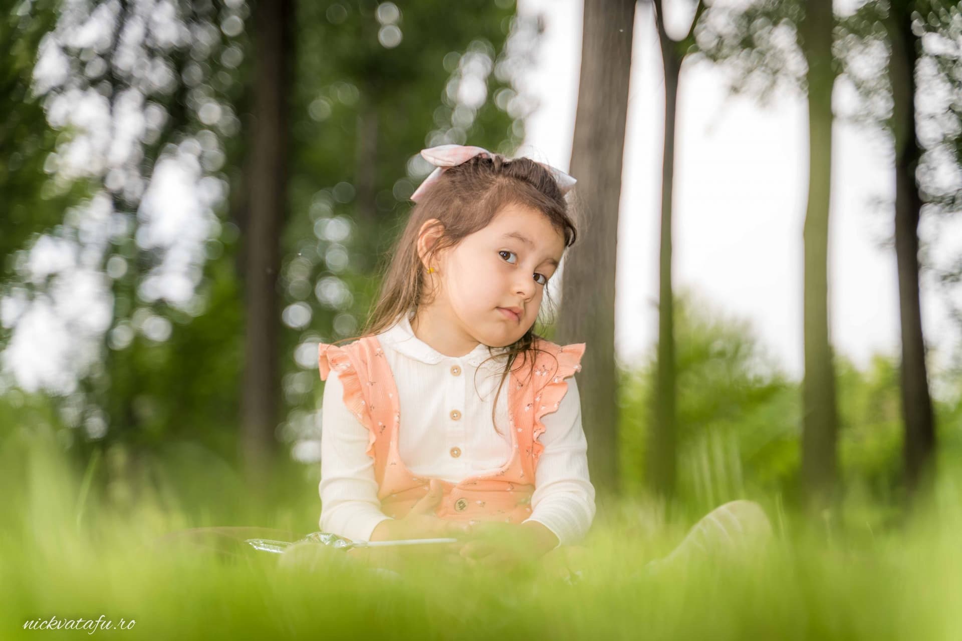 Fetiță cu rochie roz, privind cu curiozitate în natură, perfectă pentru detalii de nuntă sau botez Pitești.