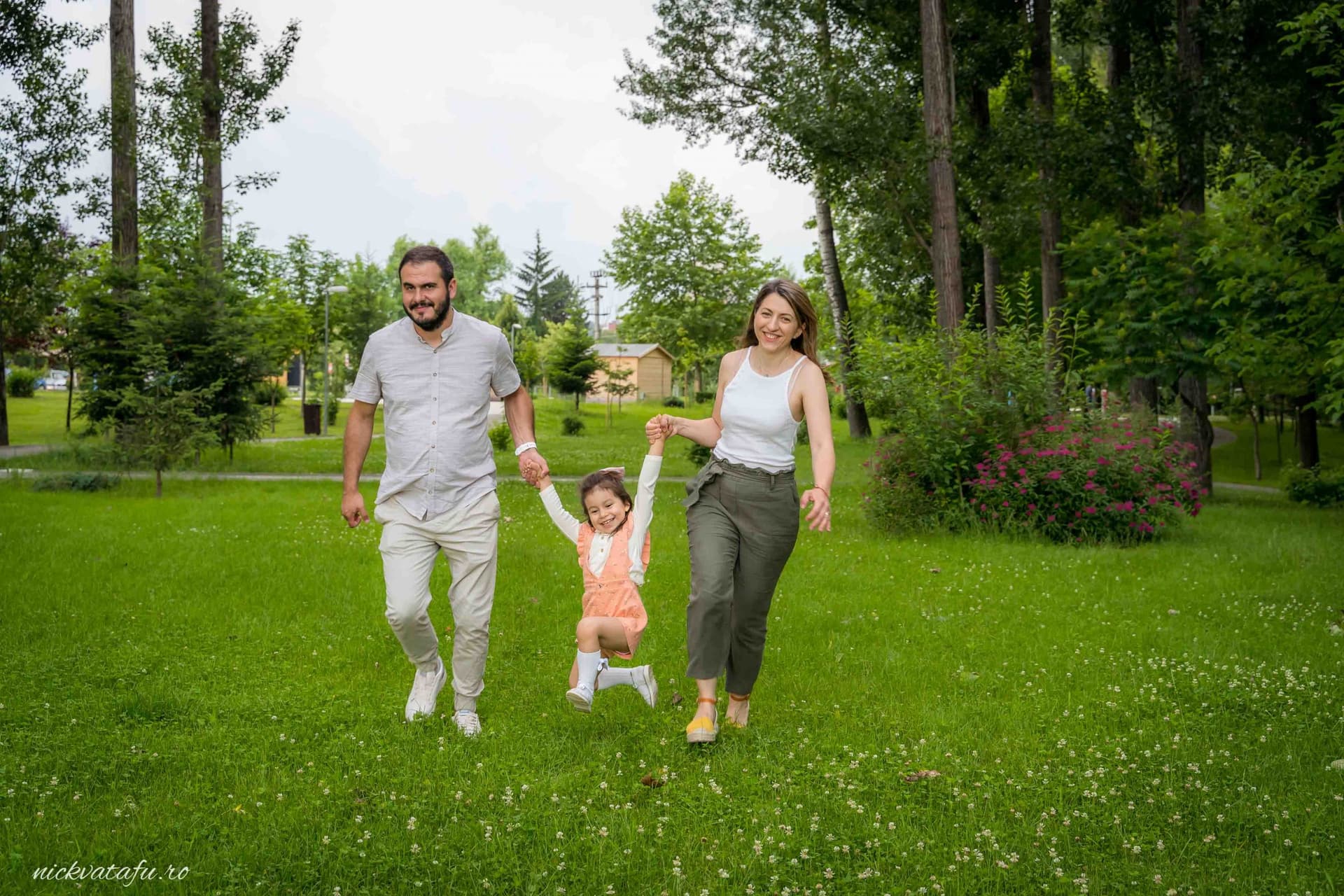 Familie fericită alergând pe iarbă, bucurie și emoție, perfect pentru o fotografie de botez în natură.