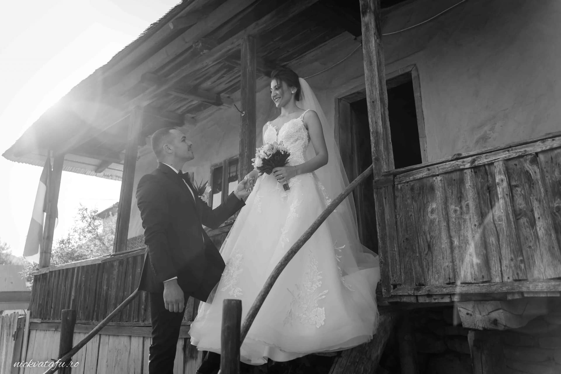 Mire și mireasă pe o scară rustică, zâmbete pline de emoție, fotografie nuntă în stil vintage.