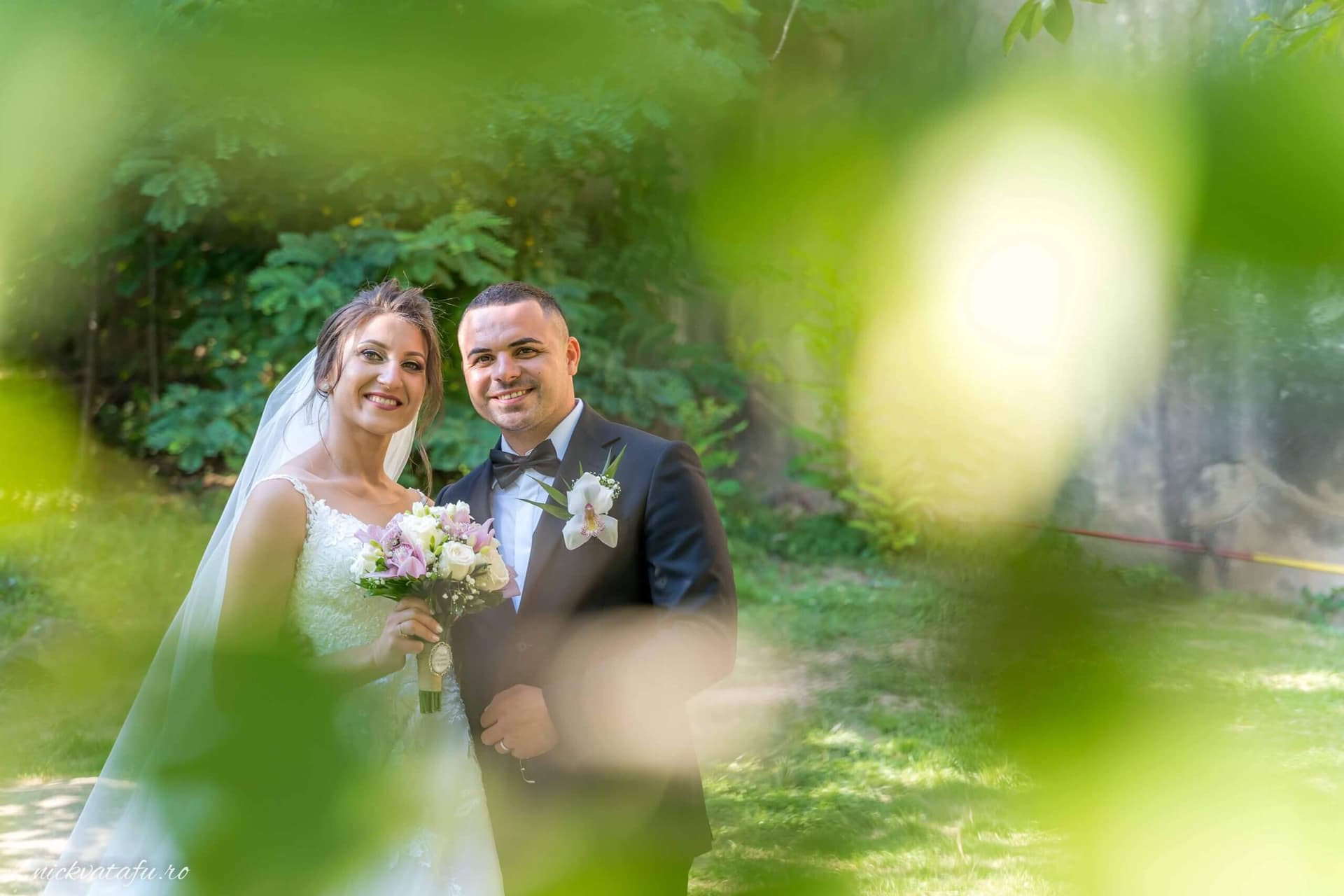 Mire și mireasă zâmbind fericiți într-un cadru natural, fotografie de nuntă cu detalii romantice.