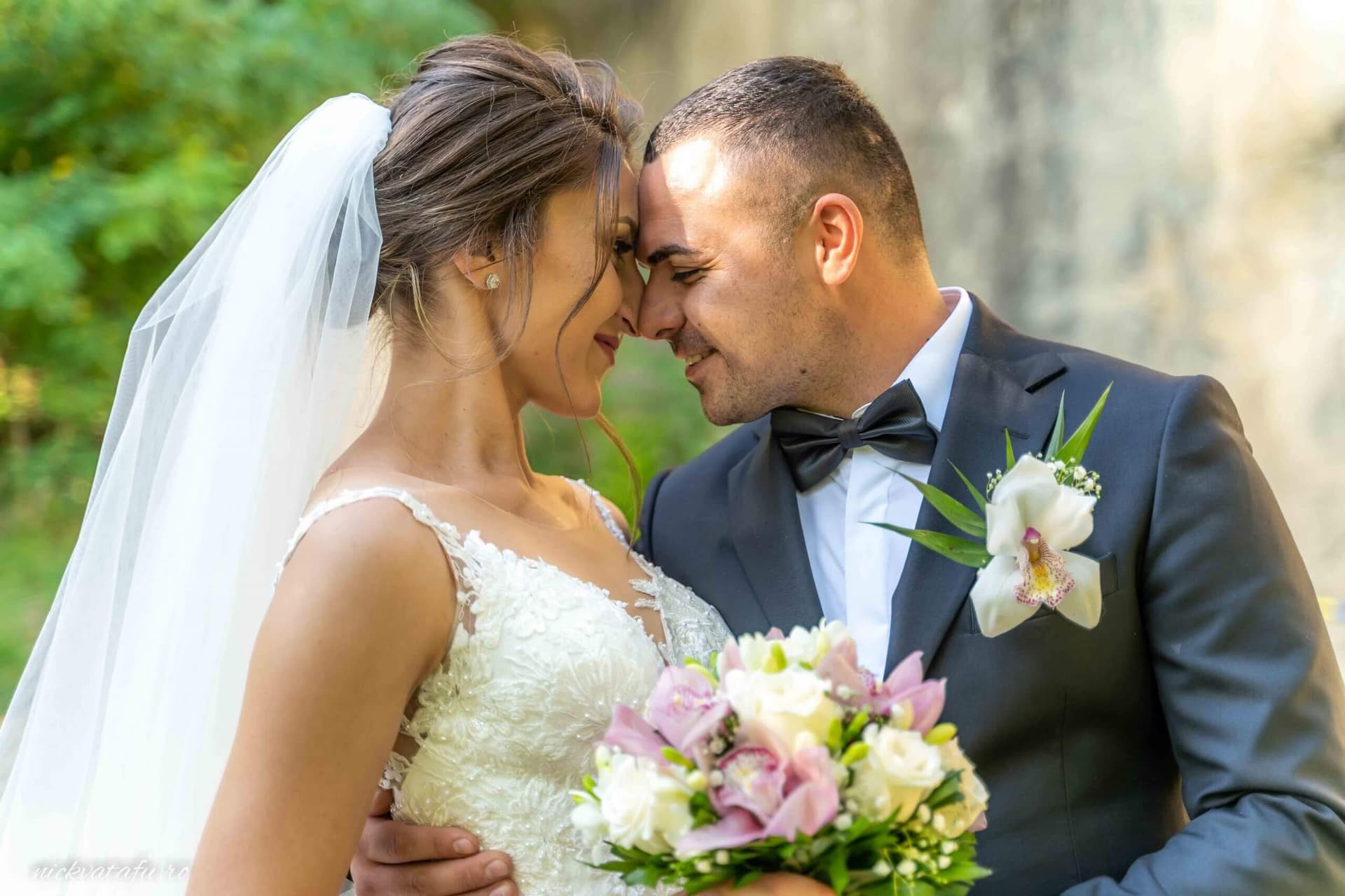 Mire și mireasă zâmbind și atingându-se frunțile, fotografie de nuntă plină de emoție în natură.