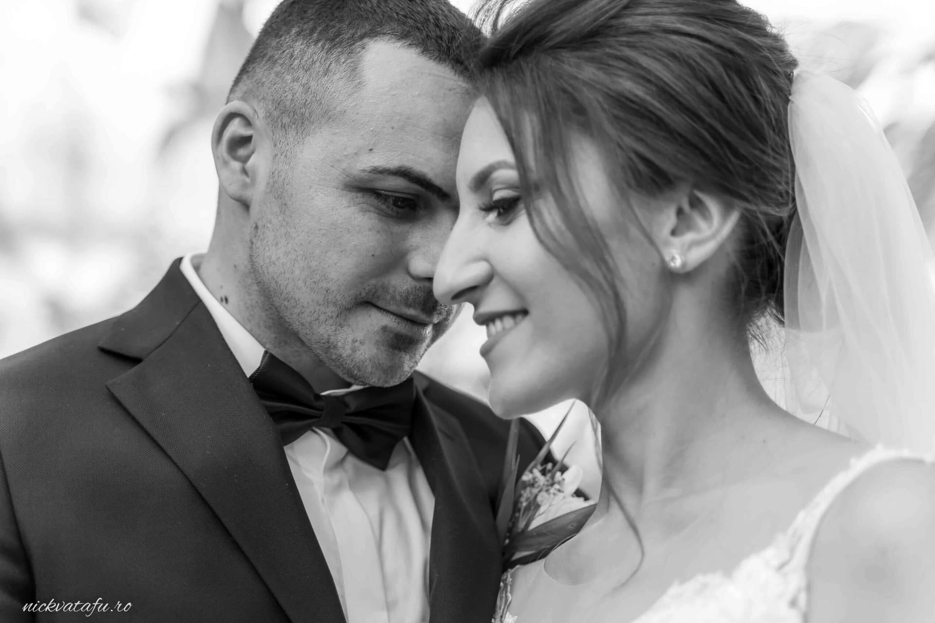 Mire și mireasă zâmbind unul la altul, emanând emoție și intimitate, fotografie nuntă în alb-negru.